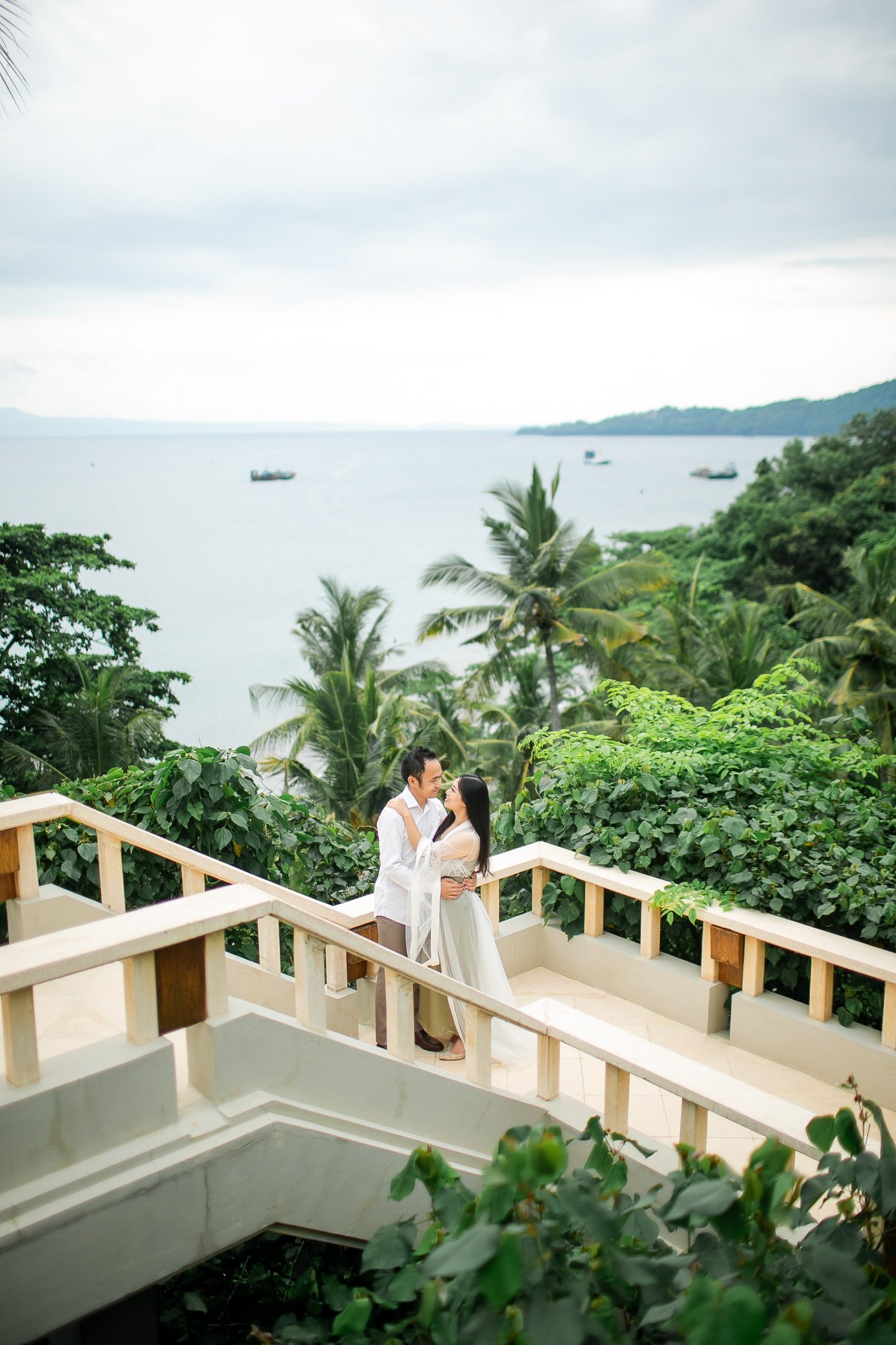 Elegant prewedding couple at Amankila Karangasem standing on ocean view stairs in East Bali