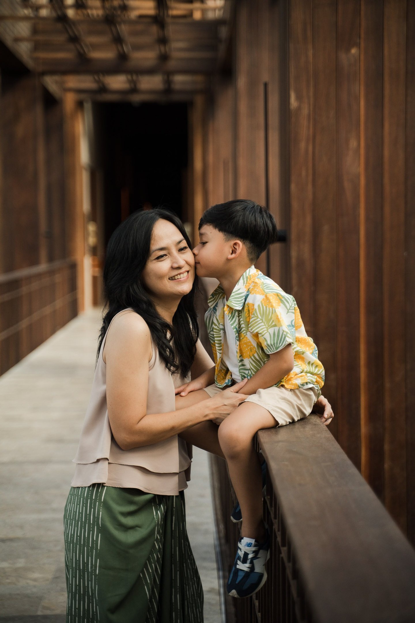 Mother and son sharing a quiet moment on a wooden bridge during a family photography session at The Meru Sanur Bali