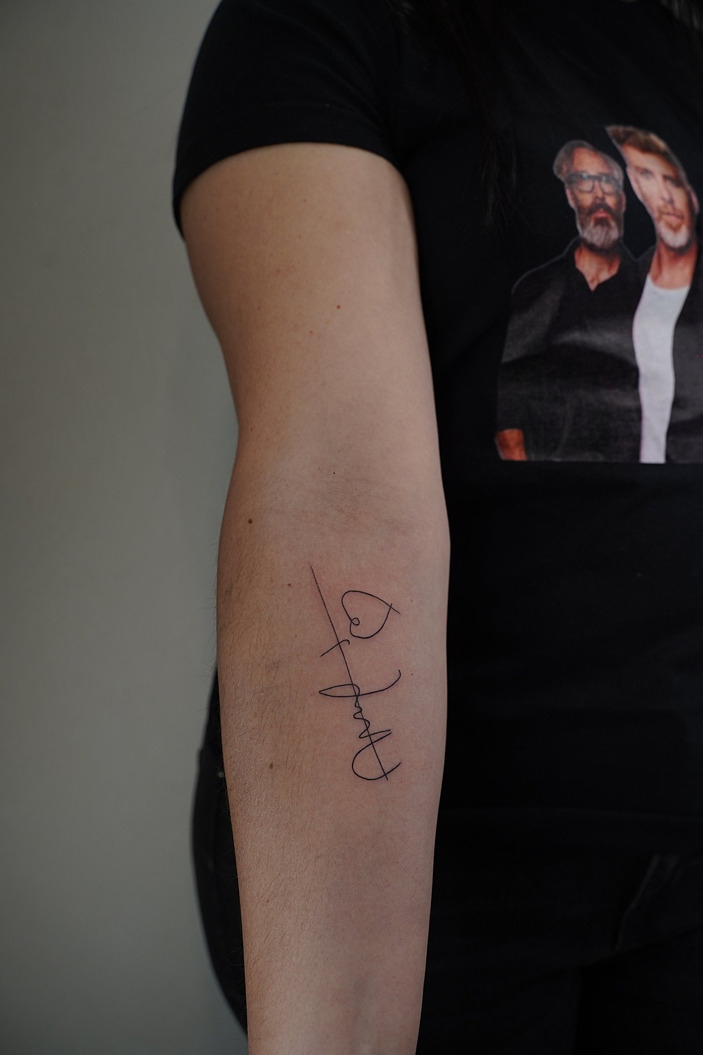 Tatuaje fineline en Madrid de diseño abstracto con línea vertical y símbolos caligráficos entrelazad