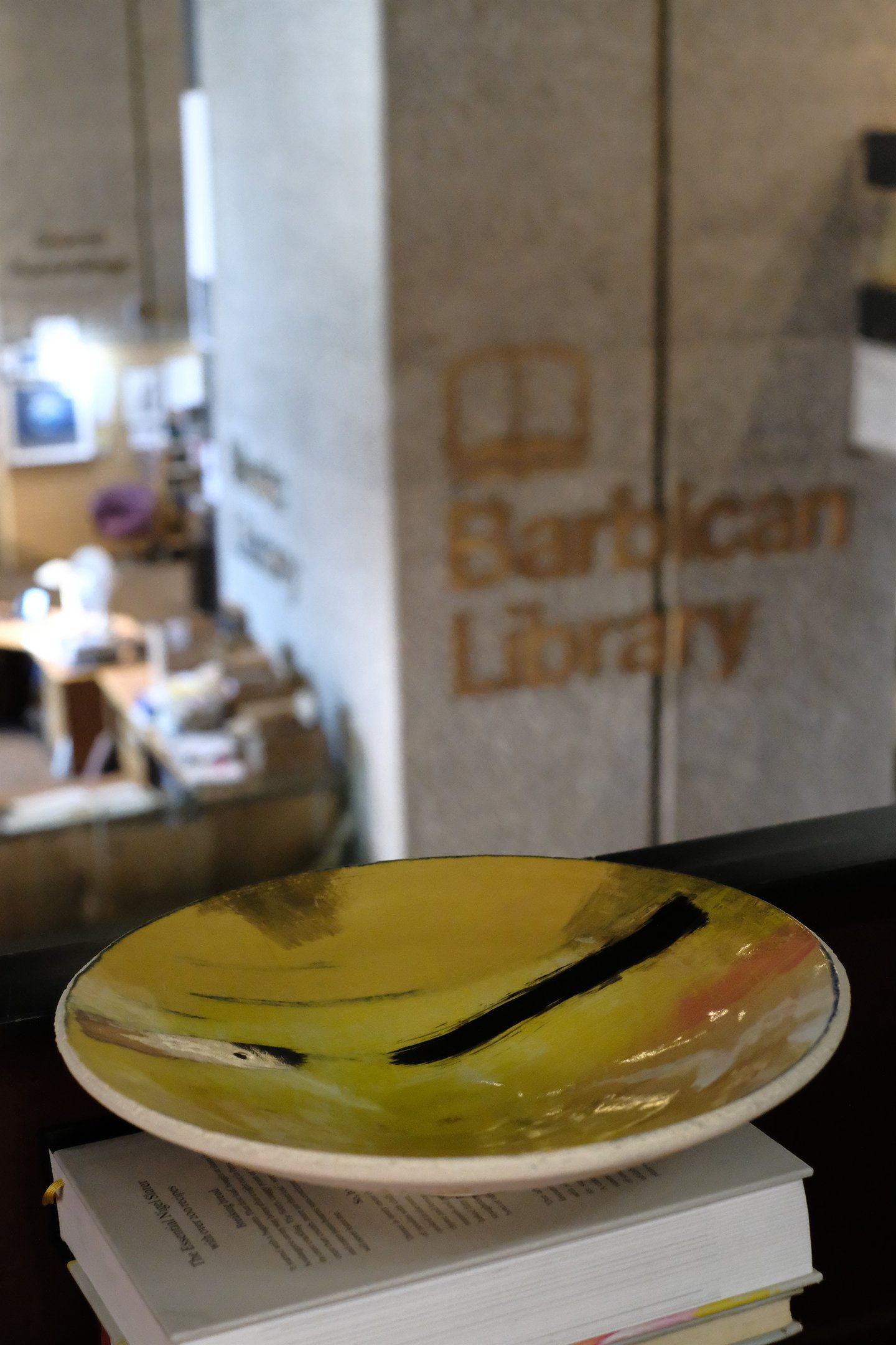 A wide low thrown ceramic bowl in white stoneware. Inside is painted with oxides and gold lustre 
