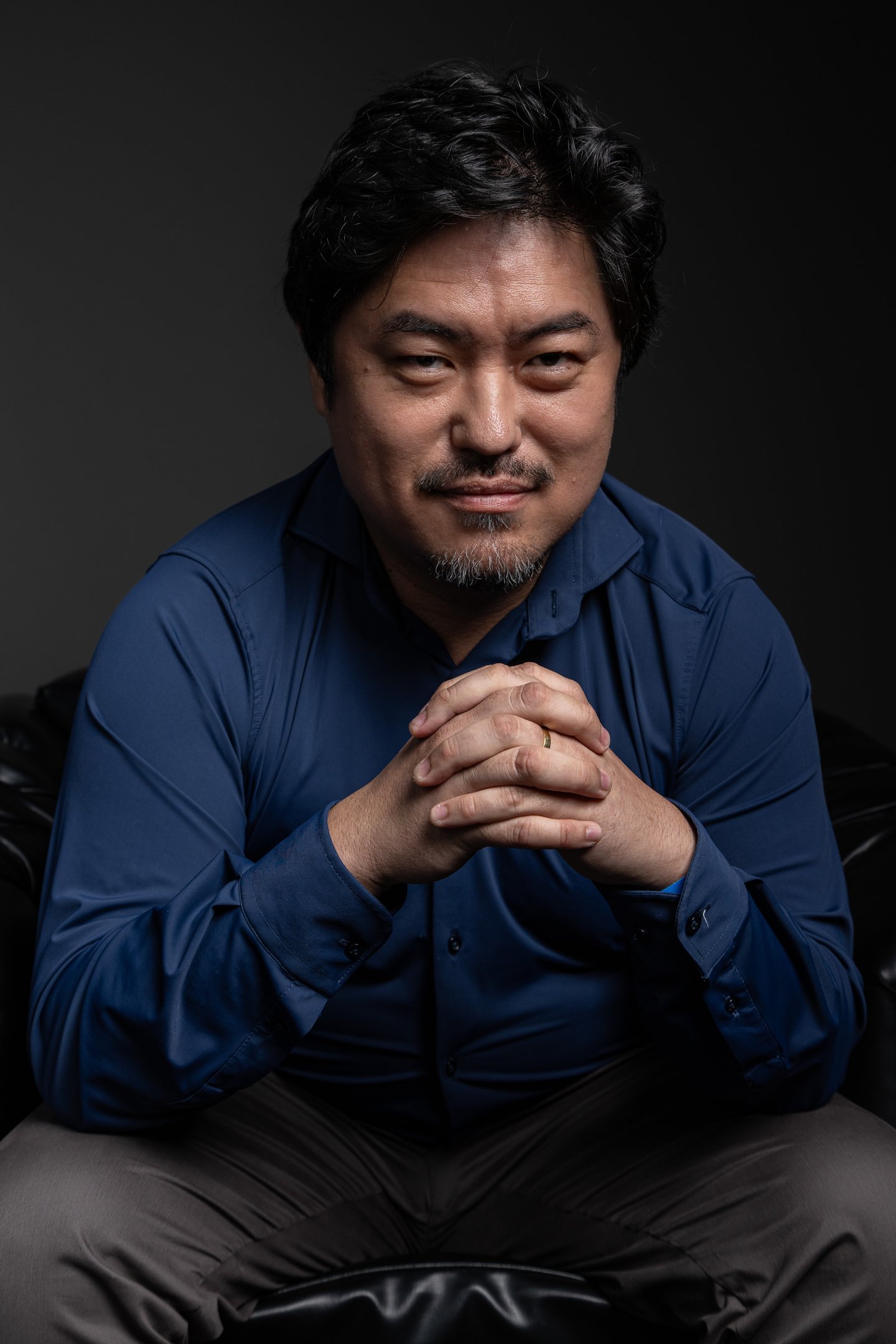 Retrato corporativo masculino em Barueri: close em estúdio com fundo escuro, expressão confiante