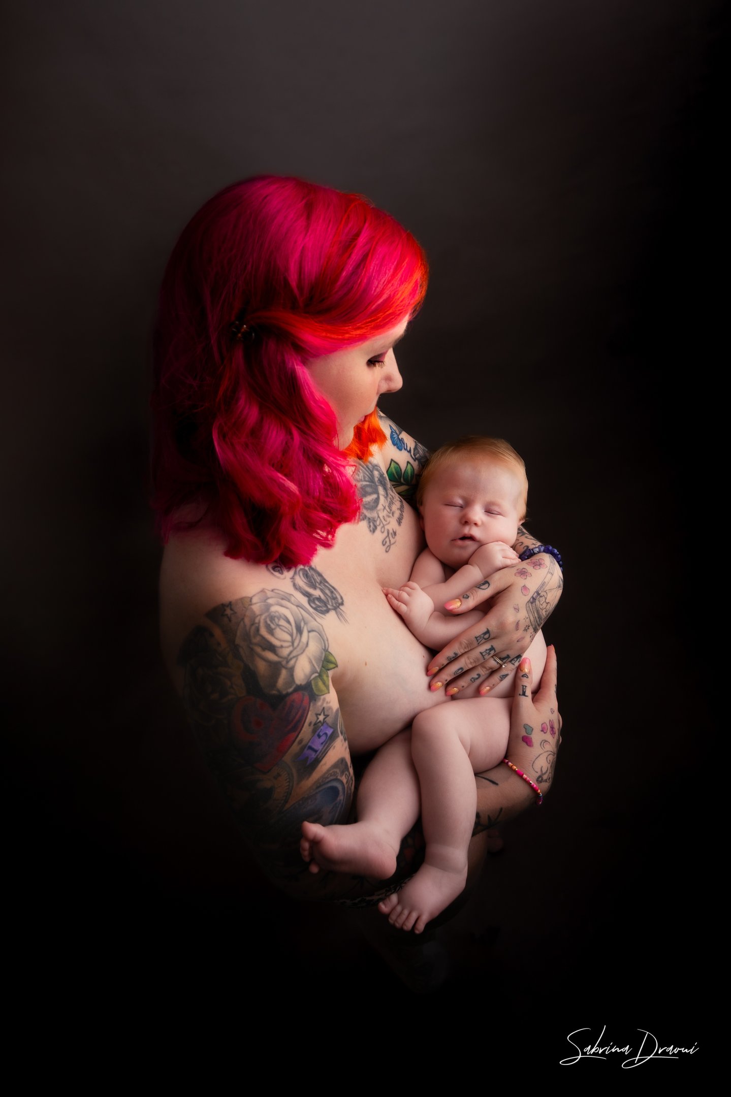 tattooed redhead woman carrying a baby