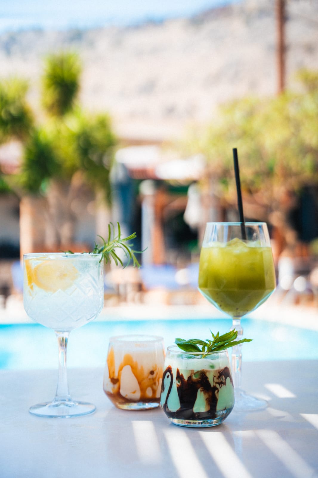 Refreshing summer cocktails and iced coffee drinks served on a patio table by Luxury swimming pool.