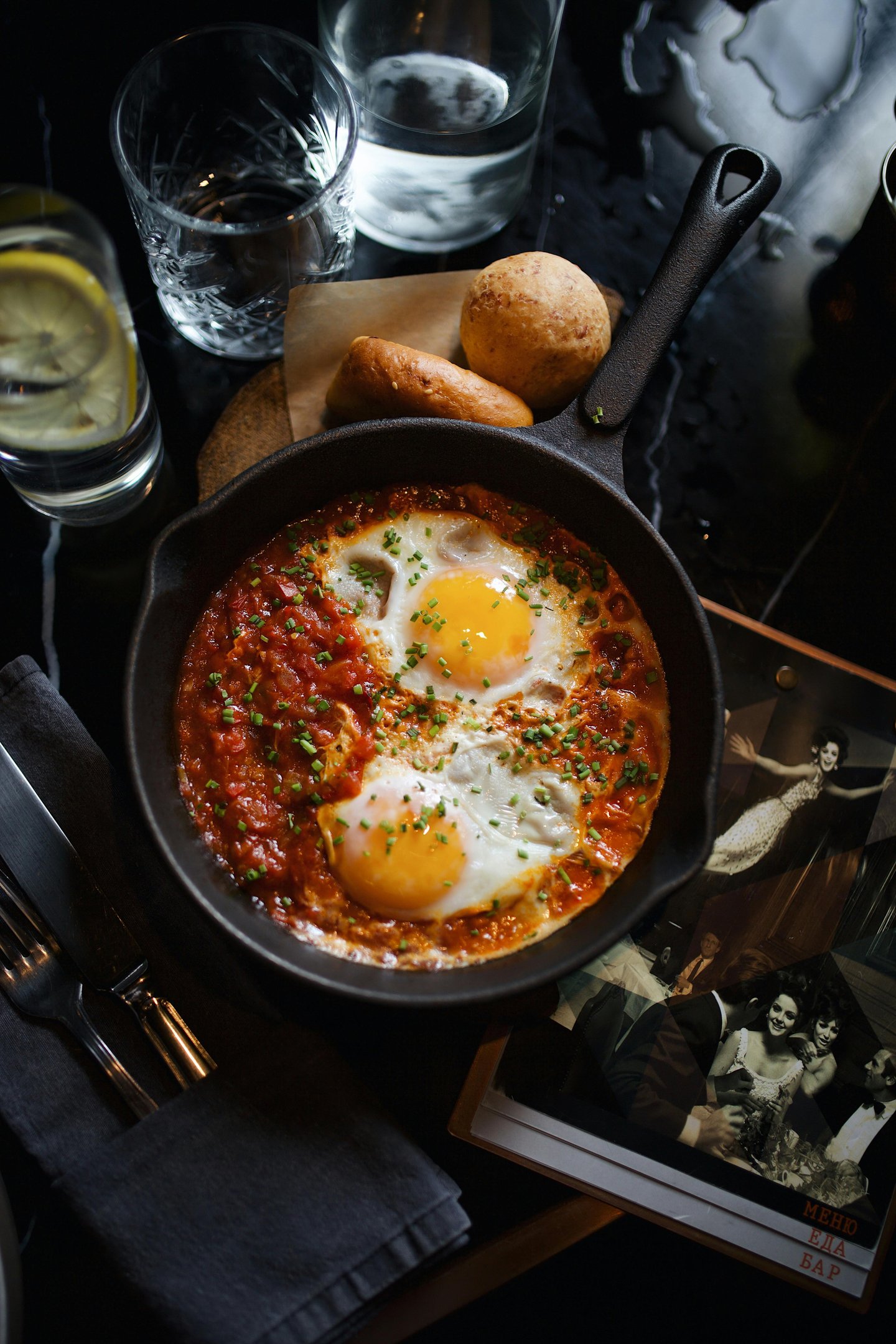 Shakshuka breakfast served in a cast iron skillet with poached eggs, tomato sauce, and fresh bread.