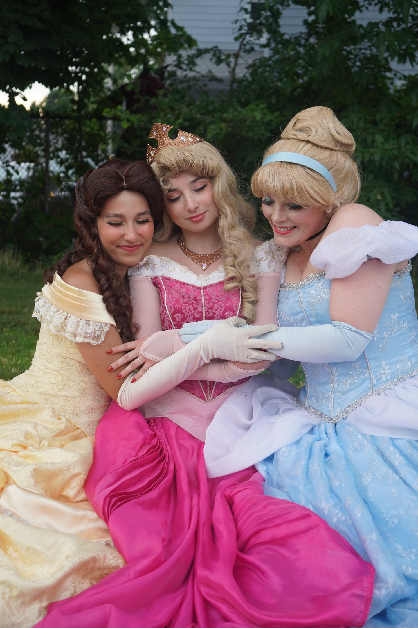 Belle, Cinderella, and Aurora share a hug