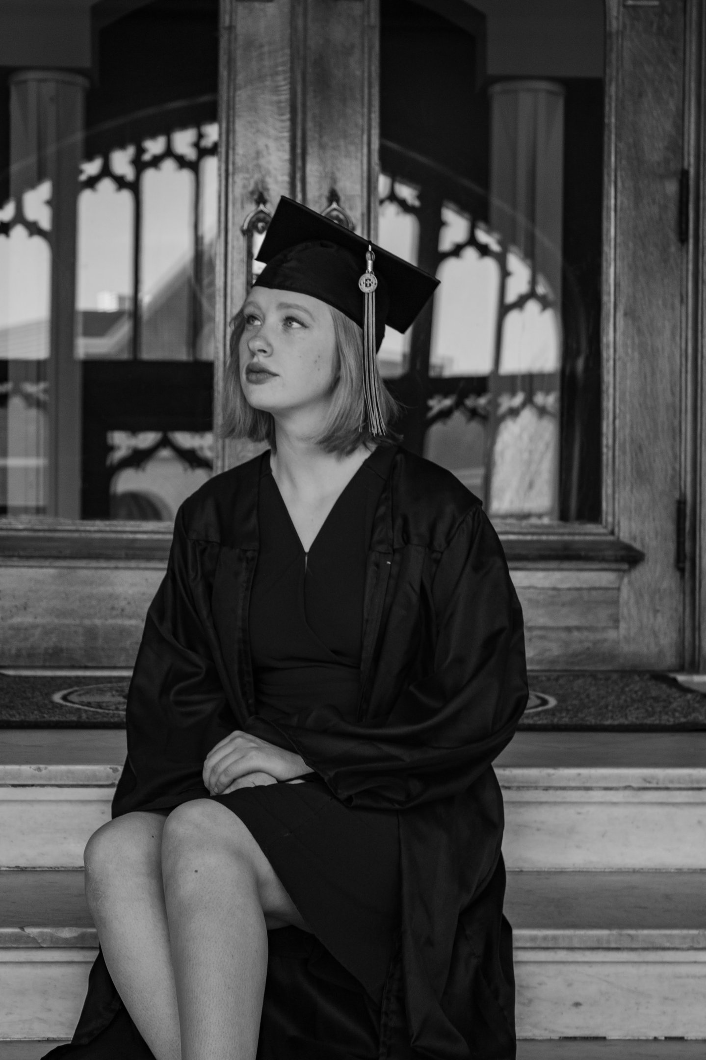 a woman in a graduation gown sitting on a bench