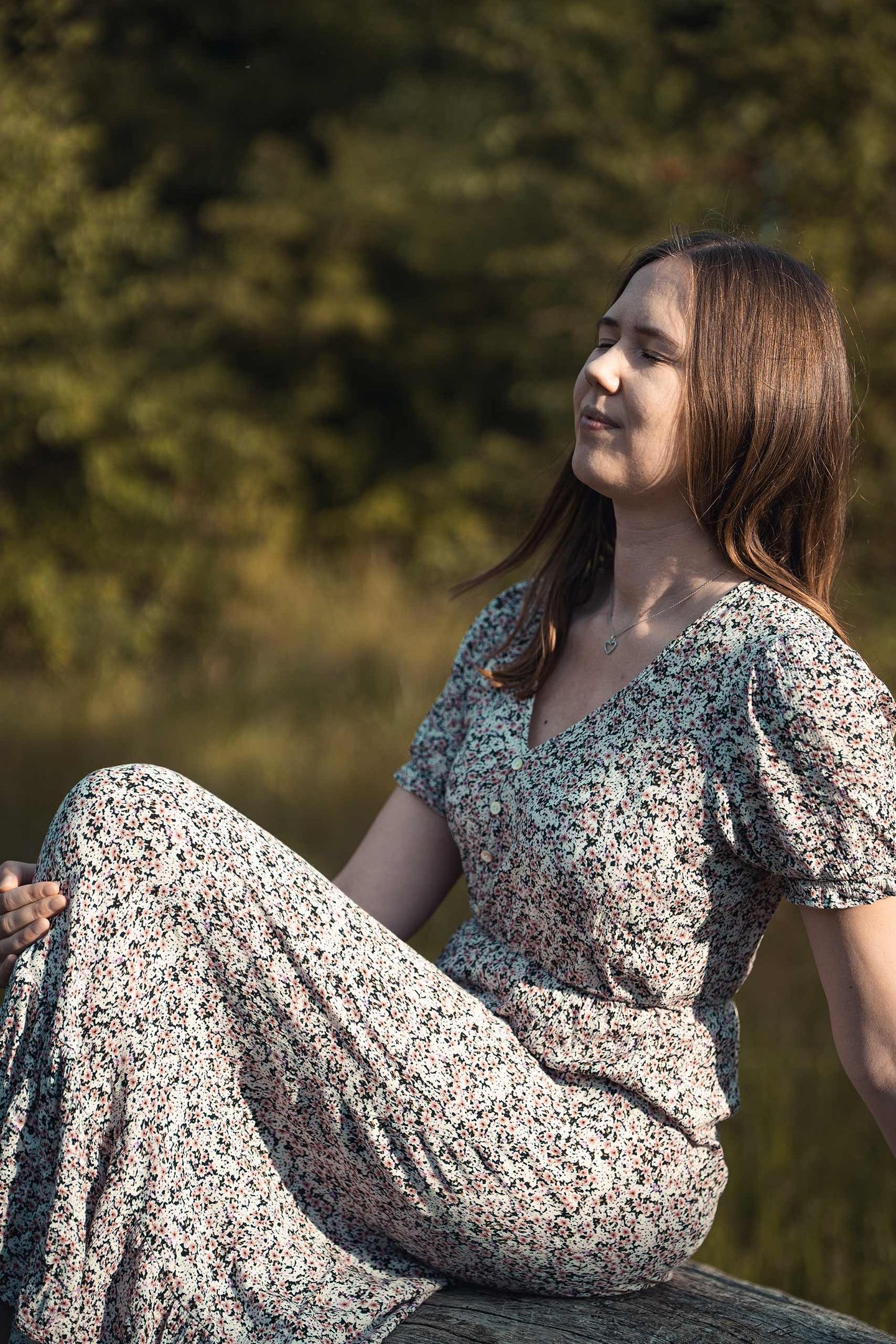 Frau im Blumenkleid sitzt entspannt in der Sonne. Natürliches Portrait von Just Perspectives.