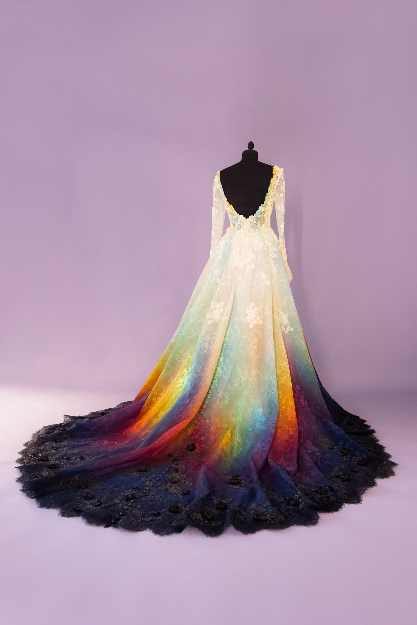 A lace wedding dress the fades from white into a rainbow of colors then into black.