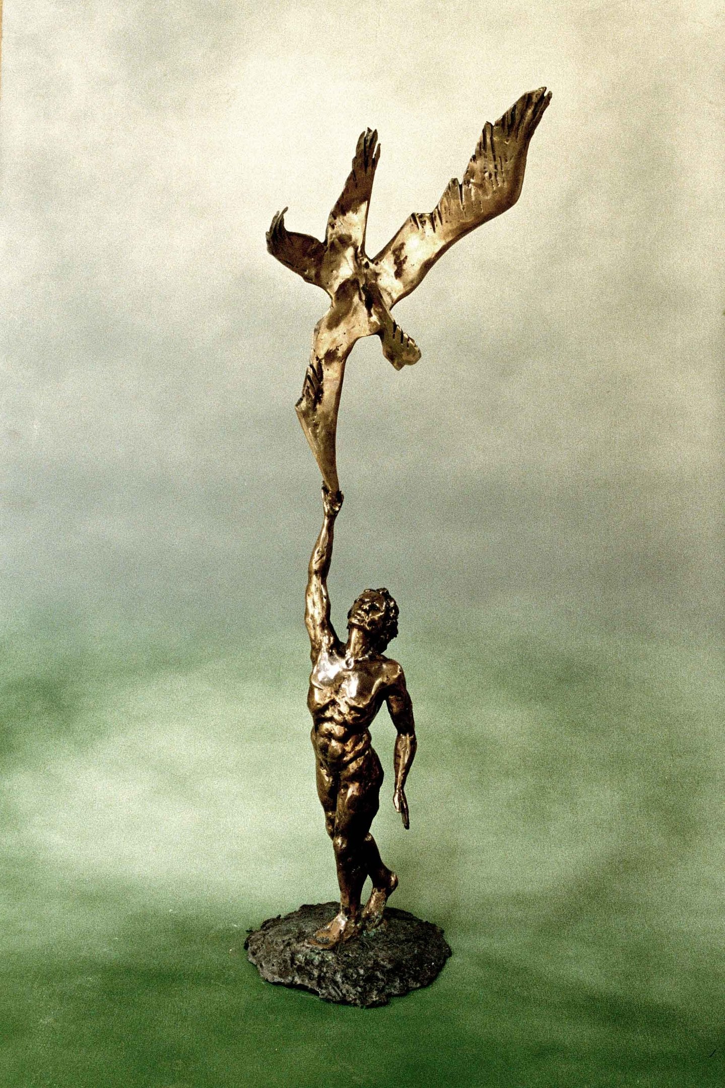 a bronze sculpture of a manreaching to touch a bird's wing