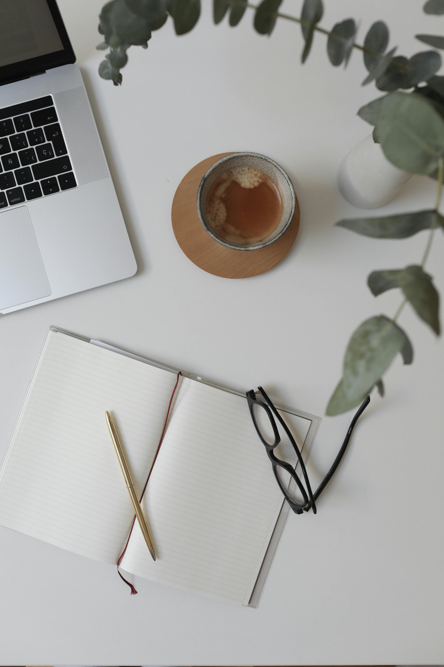 Workspace of a business operations support specialist with a laptop, coffee, and notebook