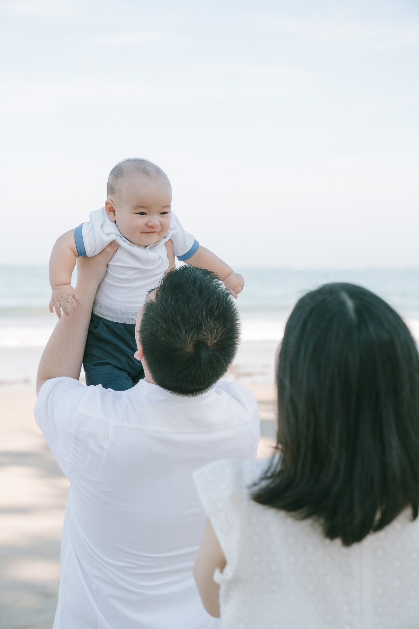 Parents lifting baby by the beach at Intercontinental Jimbaran captured in a joyful and candid family photography moment