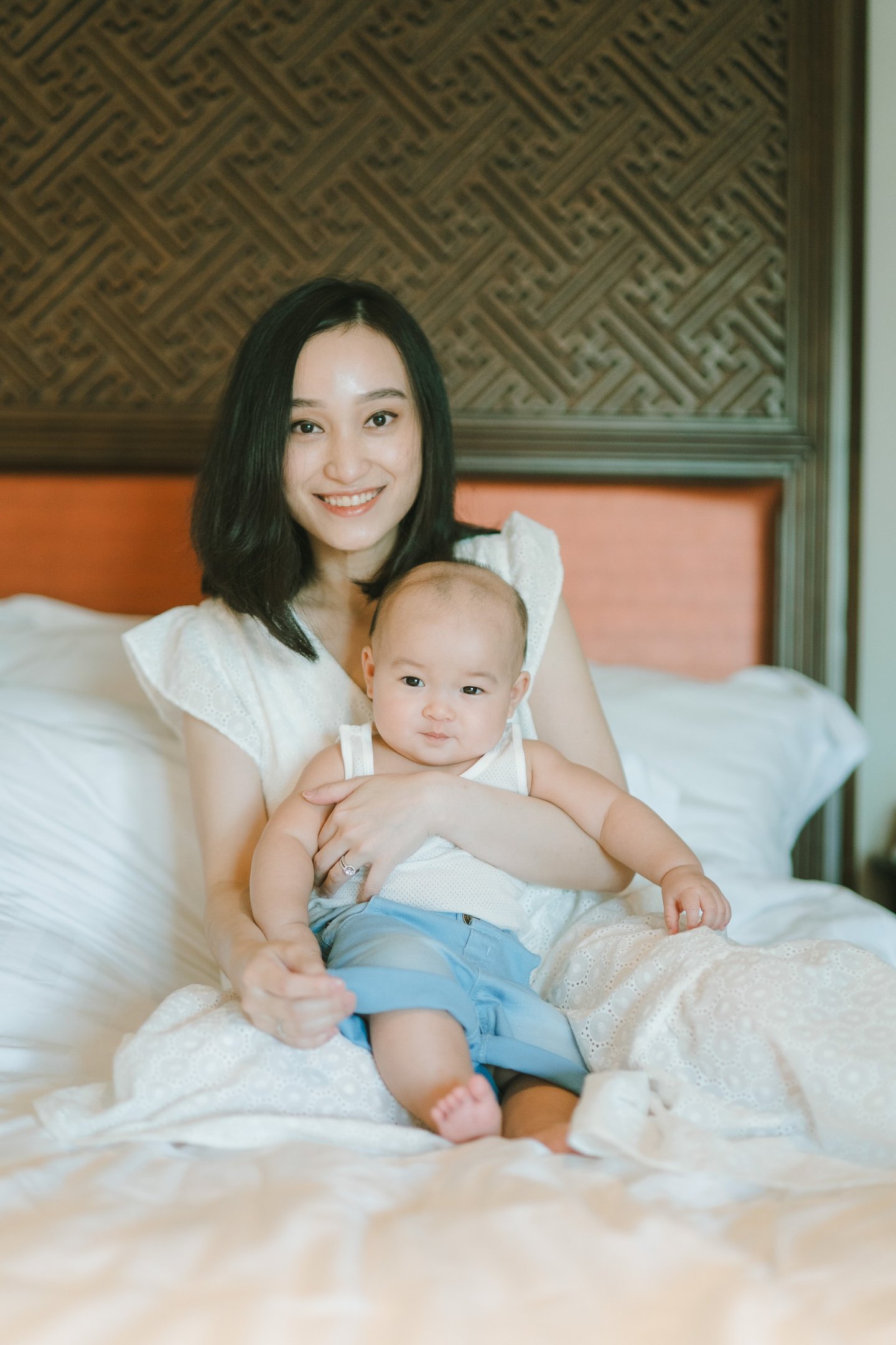 Mother holding baby on bed at Intercontinental Jimbaran in a calm and intimate family photography moment