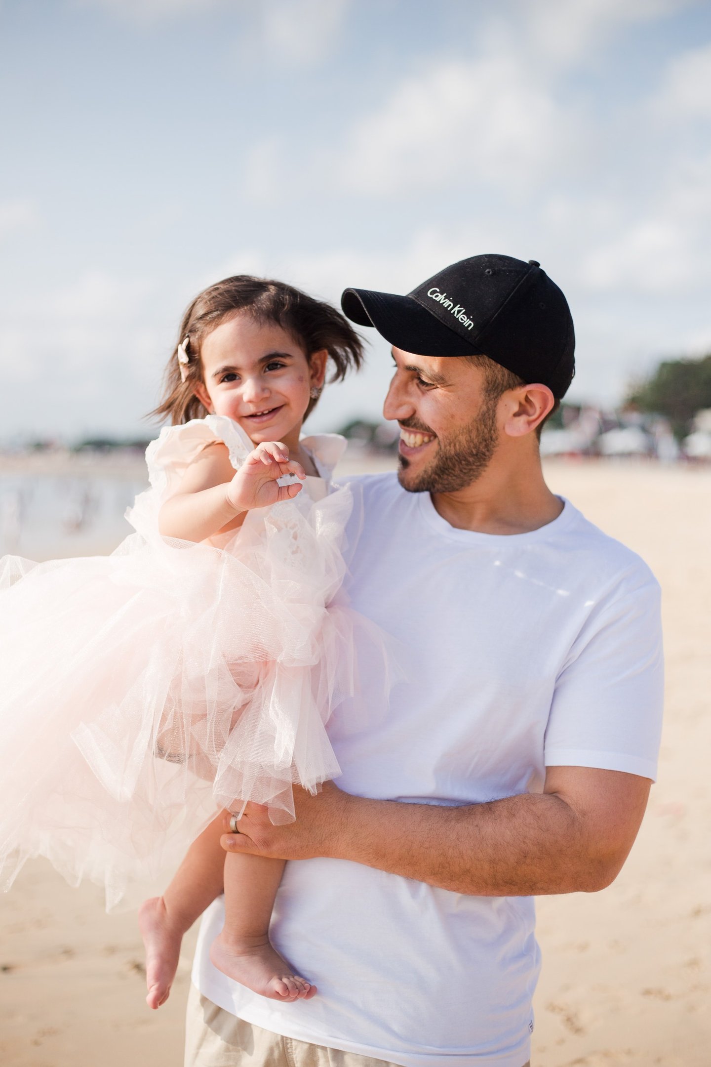 family photography session Jimbaran Beach Bali child held by father near shoreline