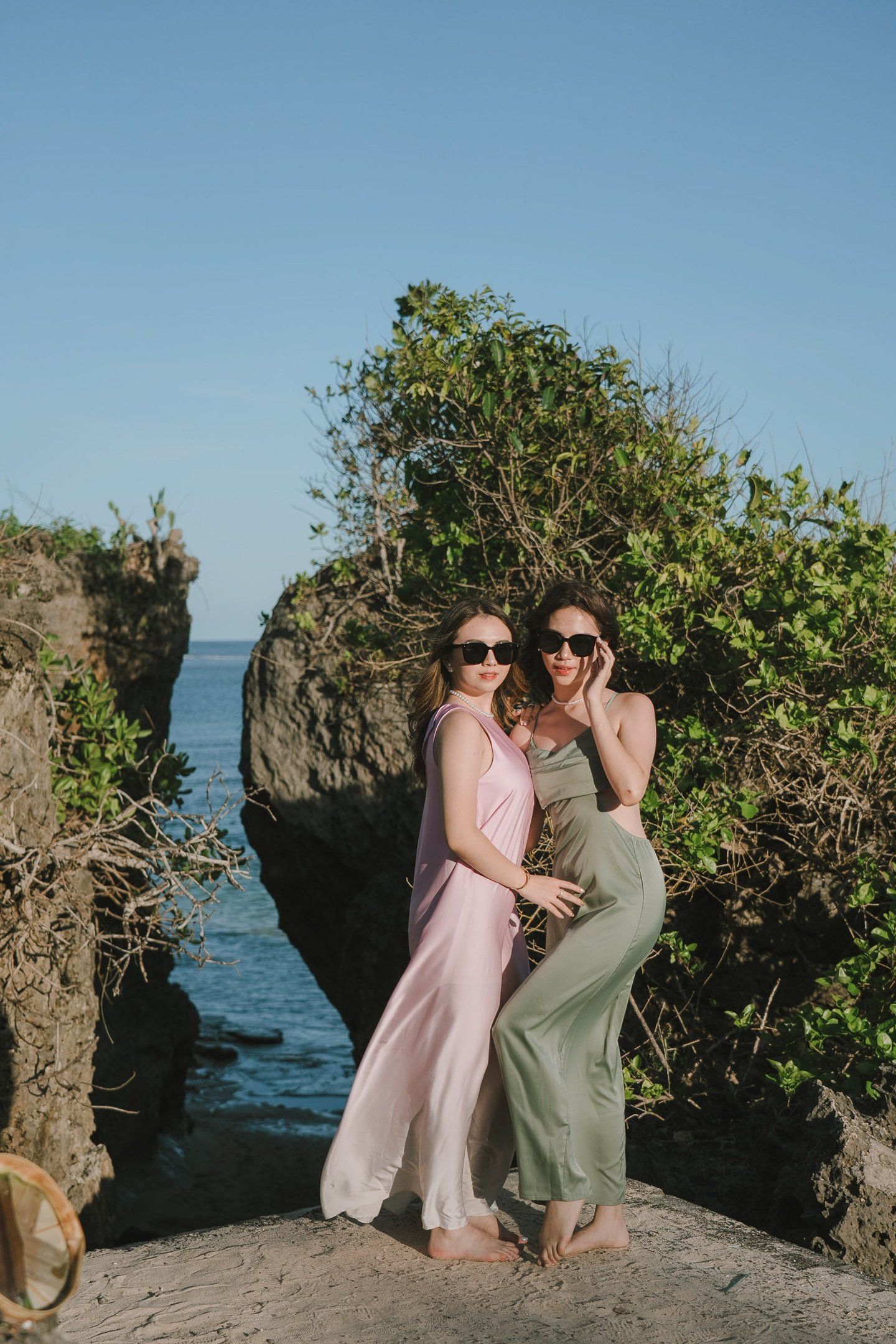 Two friends posing together on rock cliff during photoshoot at Geger Beach Nusa Dua Bali