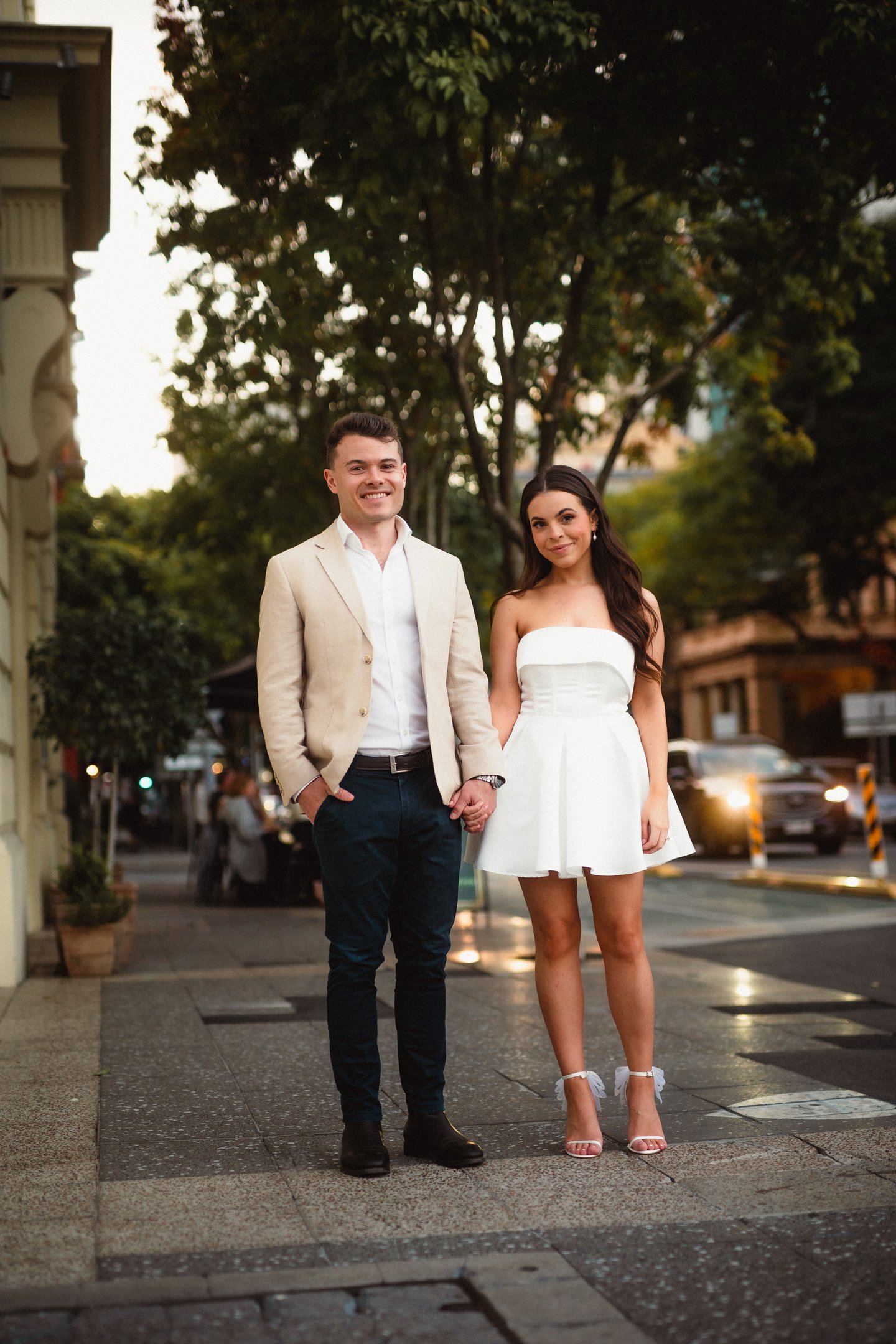 a man and woman holding hands and walking down the street