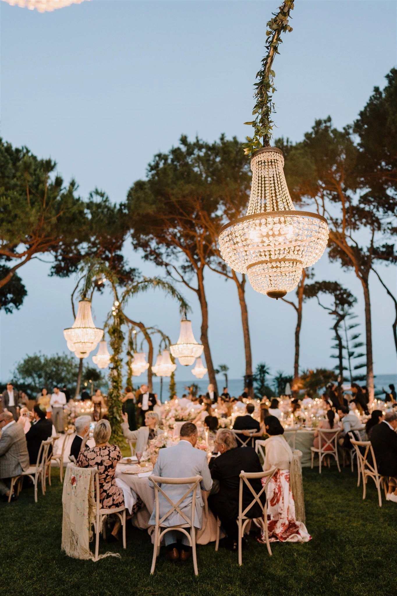 Elegant outdoor dinner at Villa El Rincon with chandeliers and guests under the trees