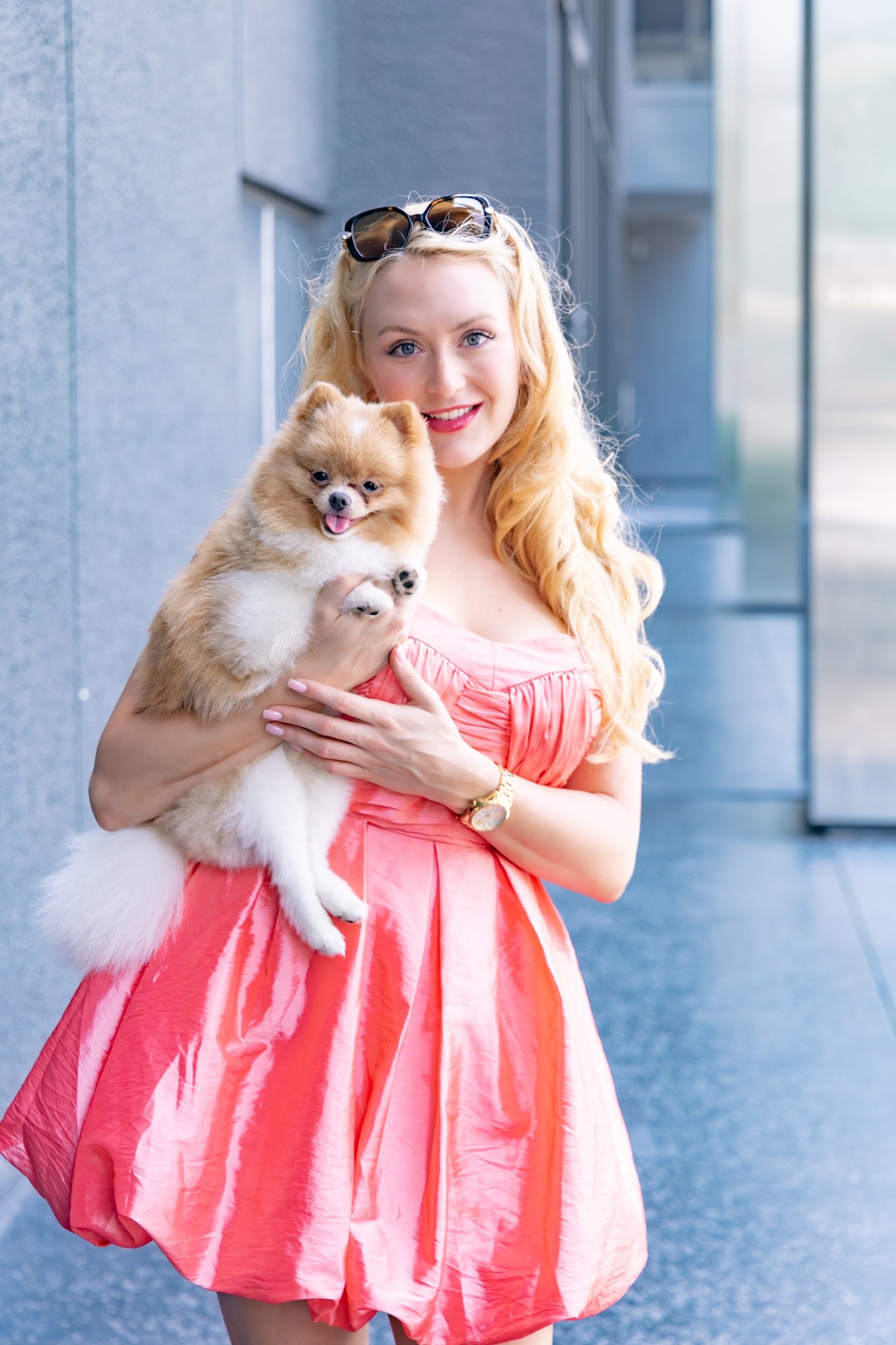 Founder of Liebe Chronicles holding Liebe, a dapper toy Pomeranian, in an urban setting.
