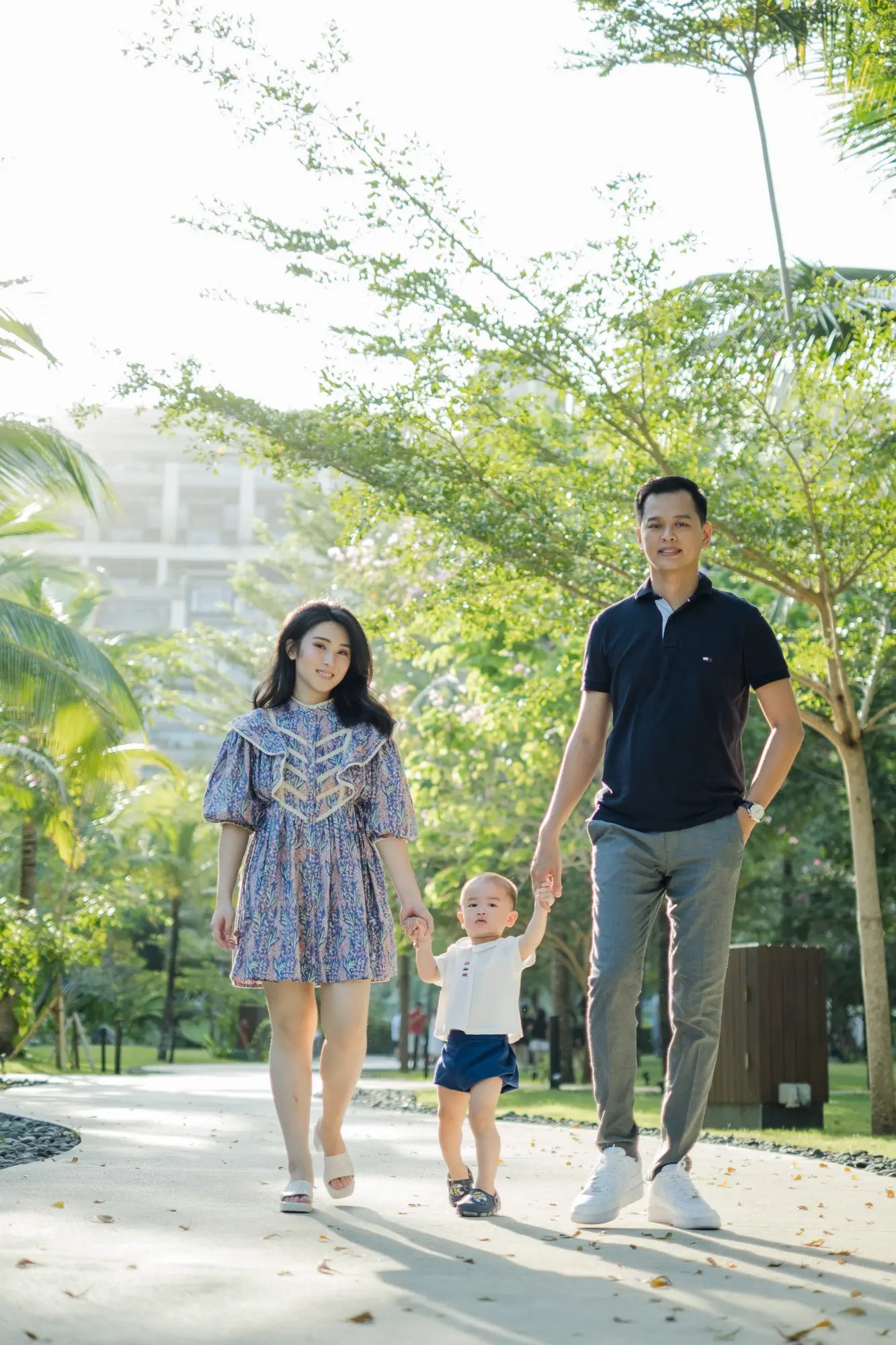 oung family enjoying a peaceful walk through the tropical gardens at The Apurva Kempinski Bali