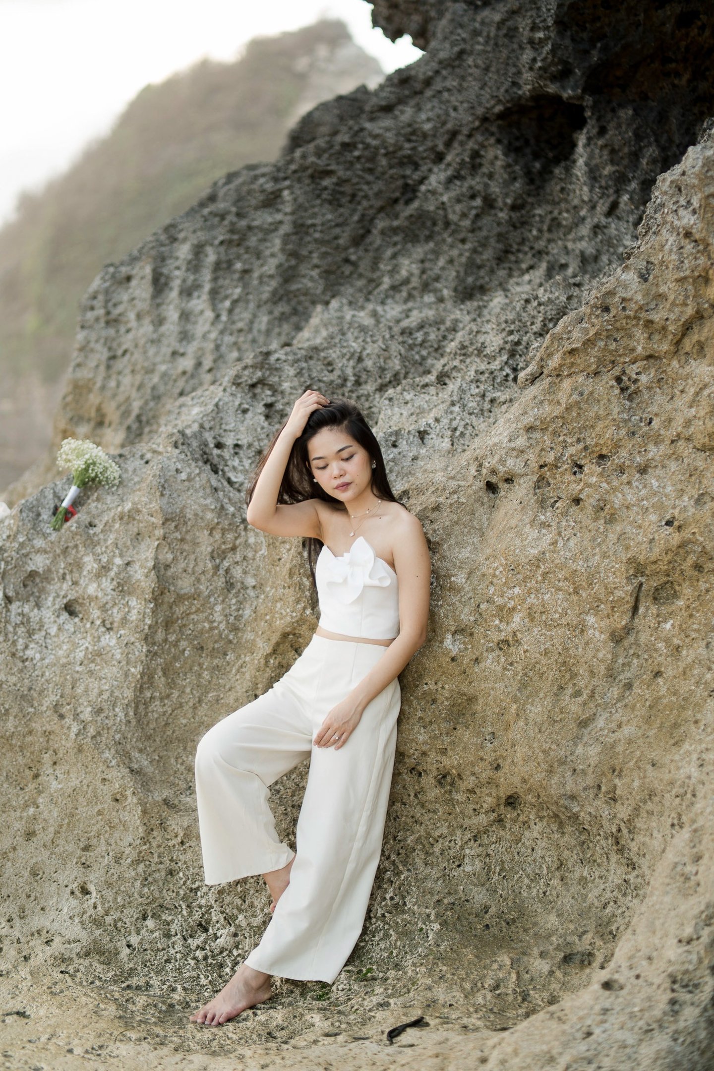 Bride portrait standing by coastal cliff during sunset photoshoot at Melasti Beach Bali