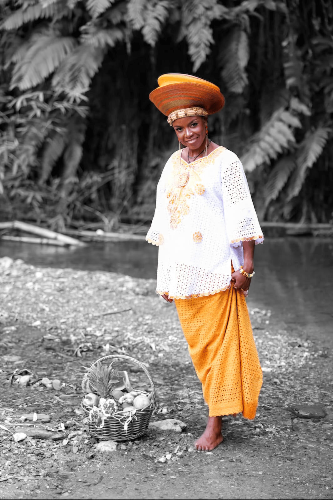 The Nutritionist in traditional African garb with a basket of fruits at a majestic river