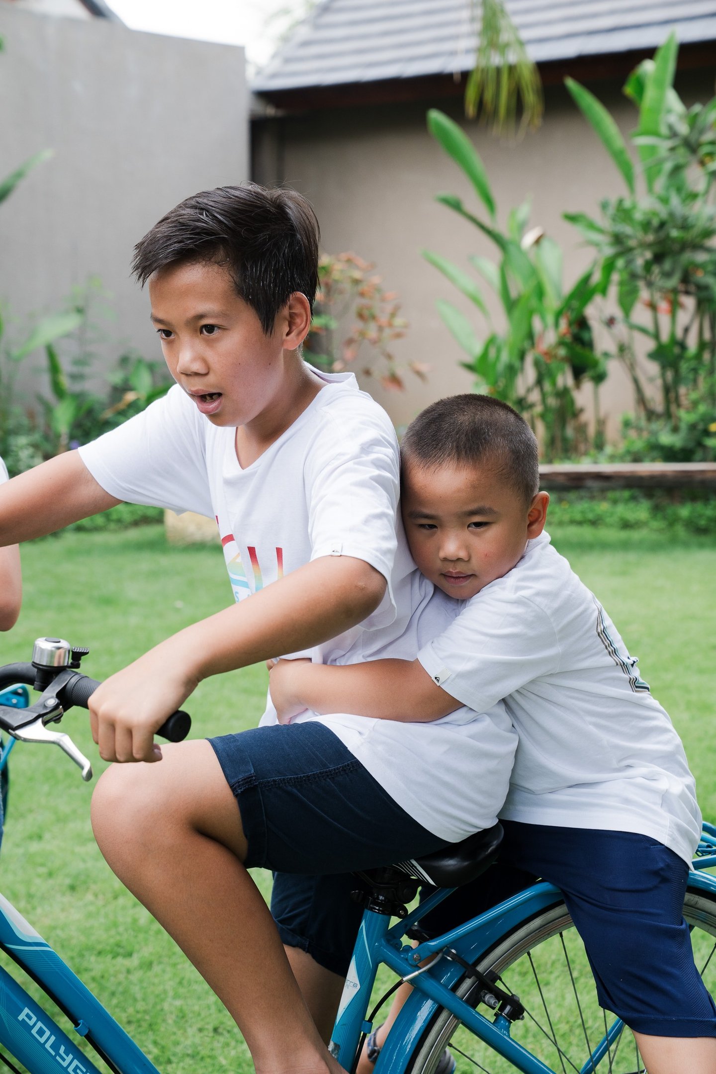 Child riding bicycle during extended family photography at Lumbini Villas Jimbaran Bali with natural candid moment