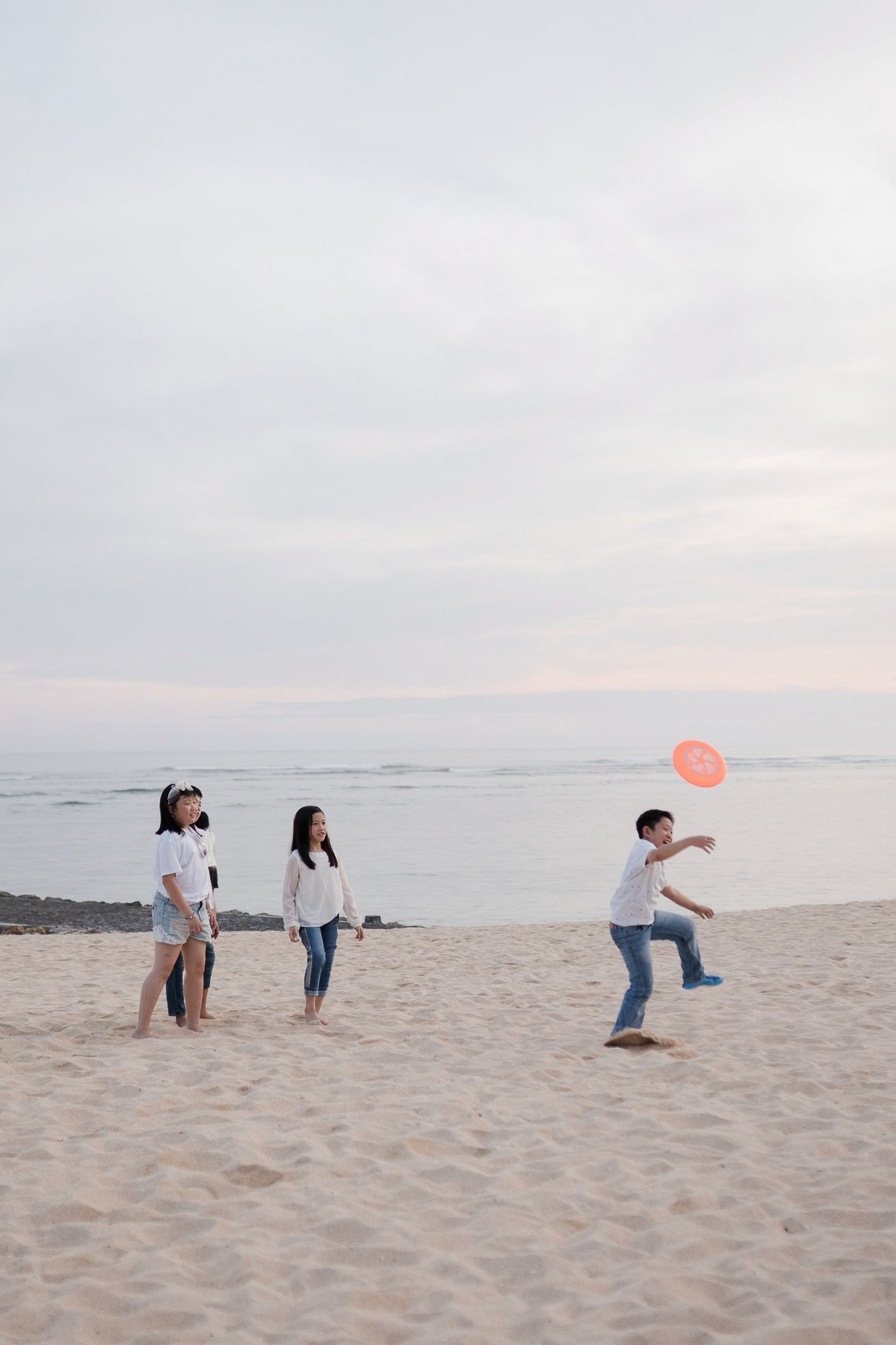 Children playing together on the beach during a relaxed family photography session at The Ritz-Carlton Bali Nusa Dua