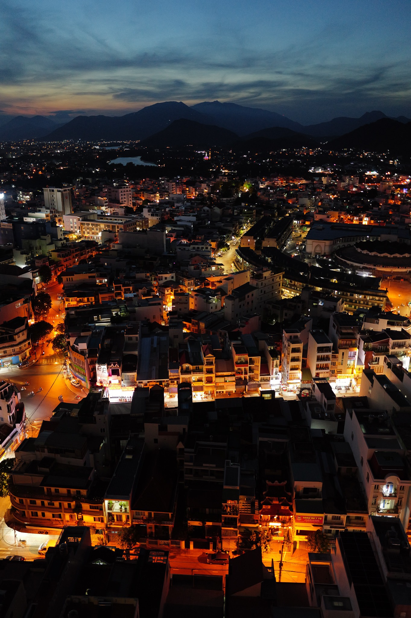 Night aerial view of Nha Trang with city lights and mountains - By ACAT Photos