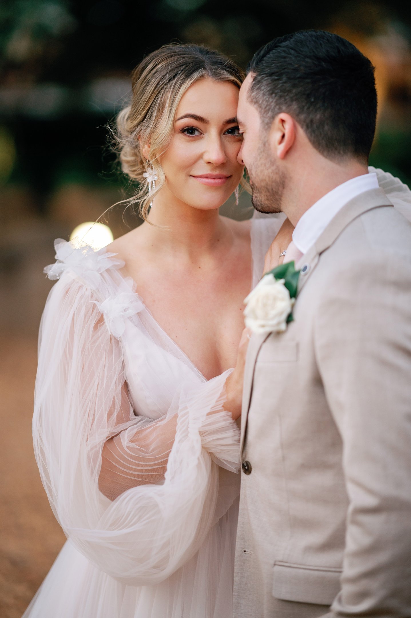 a bride and groom standing in front of a tree