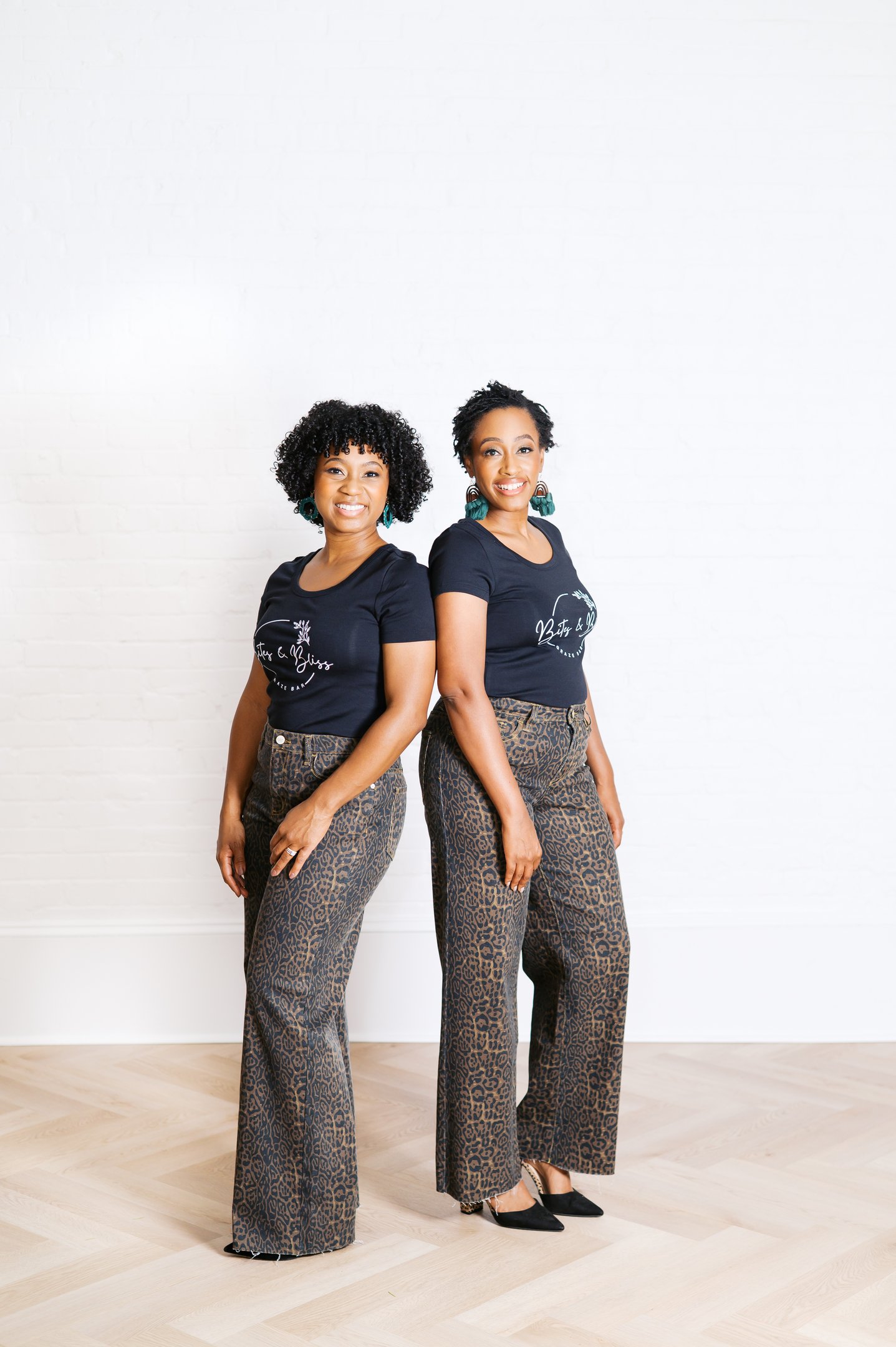 two women standing next to each other in front of a white wall