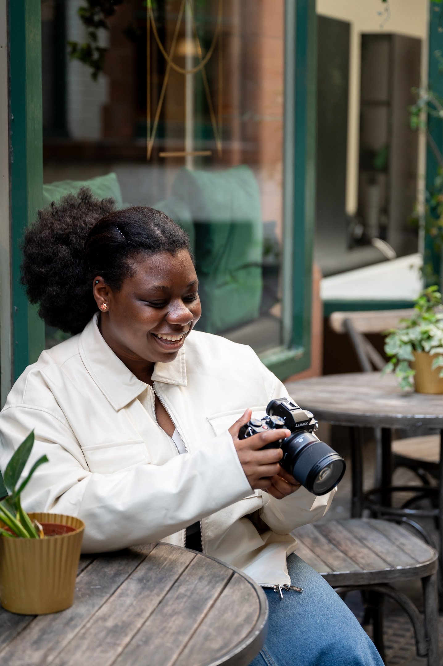 a black woman smiling in white jacket looking at outdoor photography photos