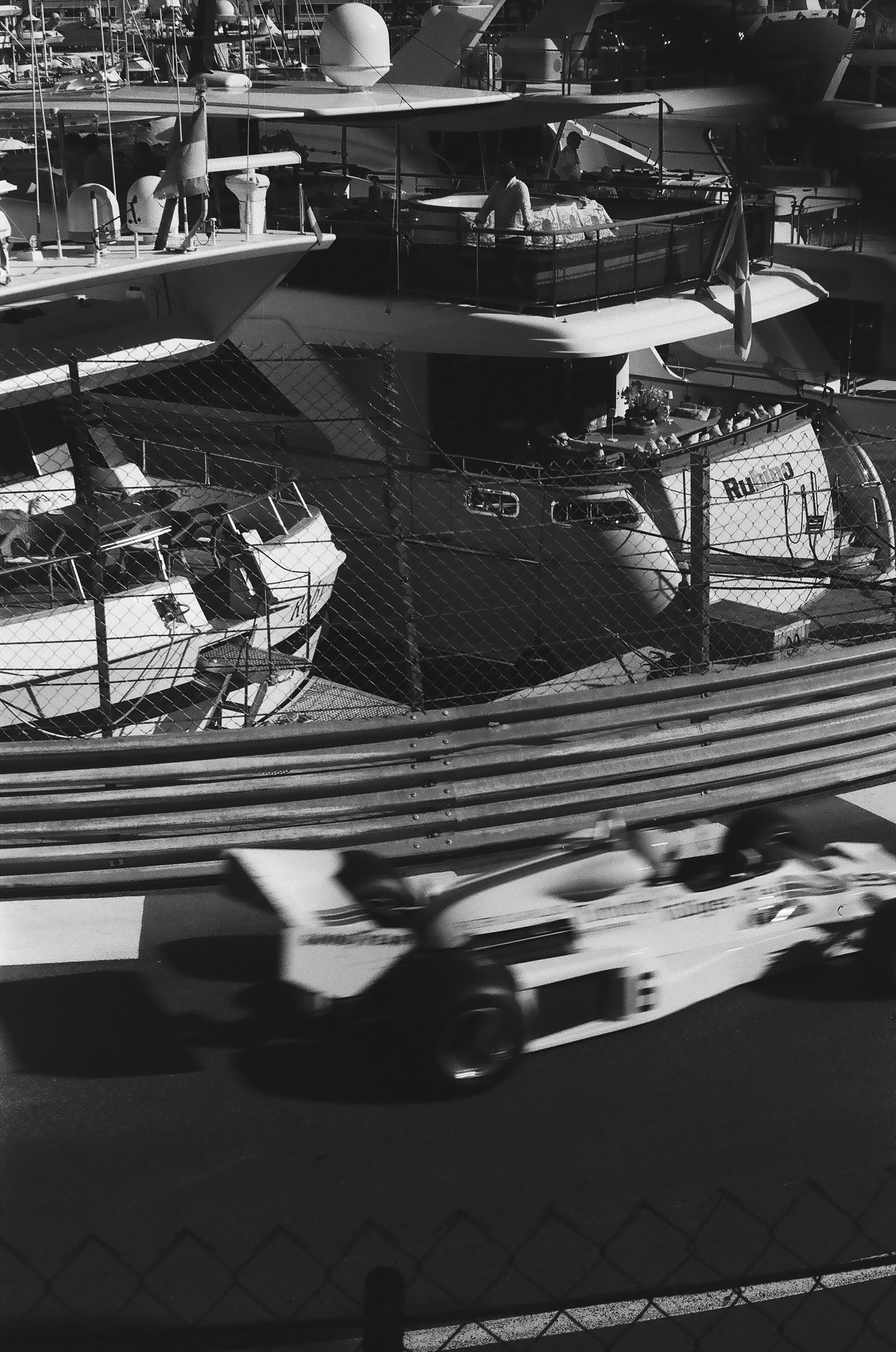 a race car racing down the track with a boat in the background in Monaco