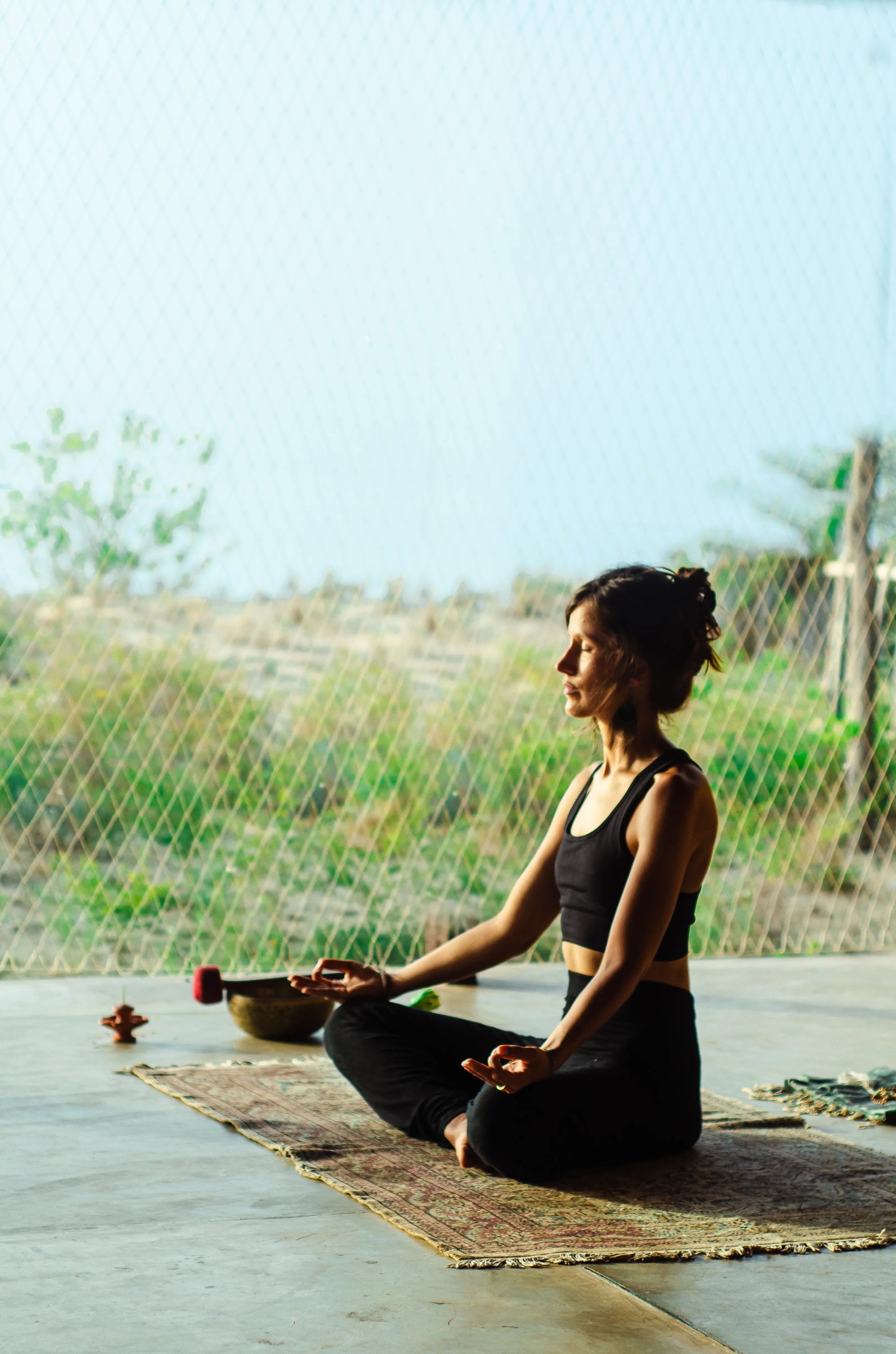 Isabel Maass meditating in yoga shala with afternoon sun, symbolizing demystifying meditation and mindful presence.