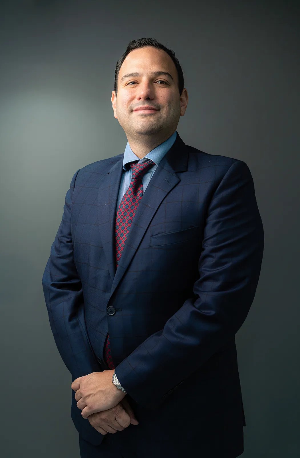 Fotografía profesional corporativo de hombre con terno azul, corbata roja en fondo gris de Quito, Ecuador