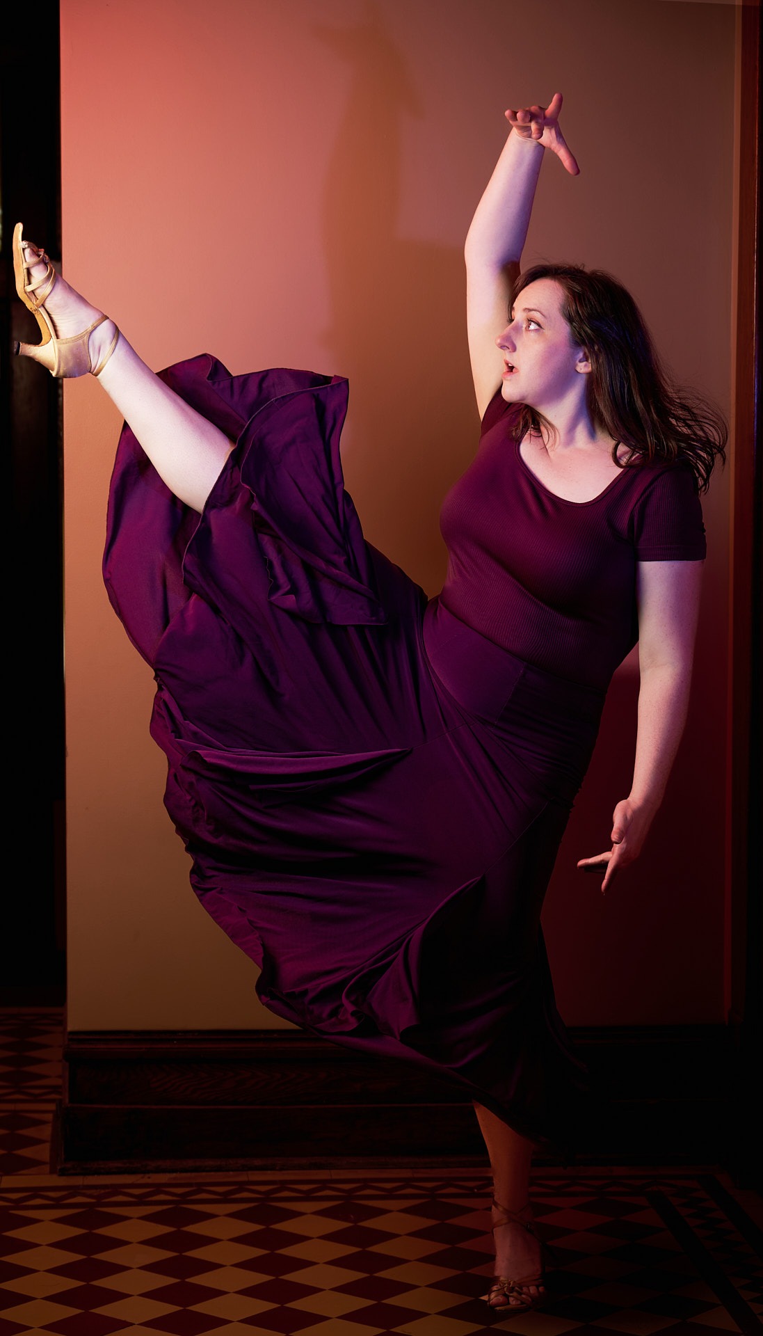 a woman in a purple dress with one leg up dancing in a latin dance style