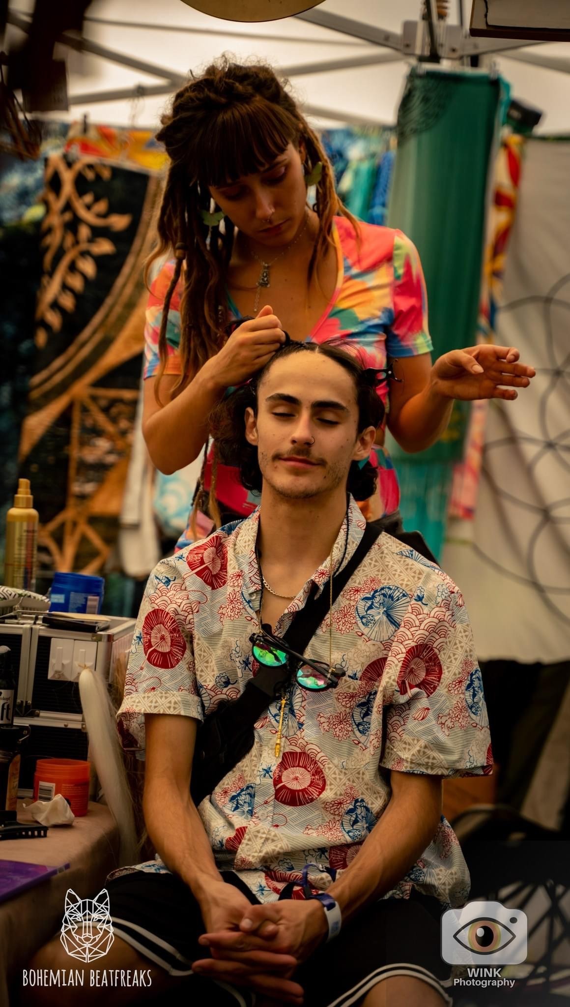 a woman braiding a mans hair at a festival