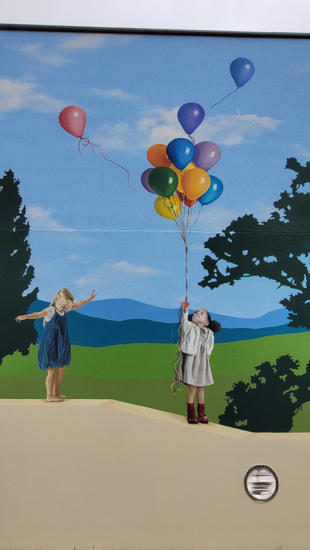 Détail d'une fresque murale: une fillette, debout, joue sur un muret. Chaufferie, Viry, Jura, 39.