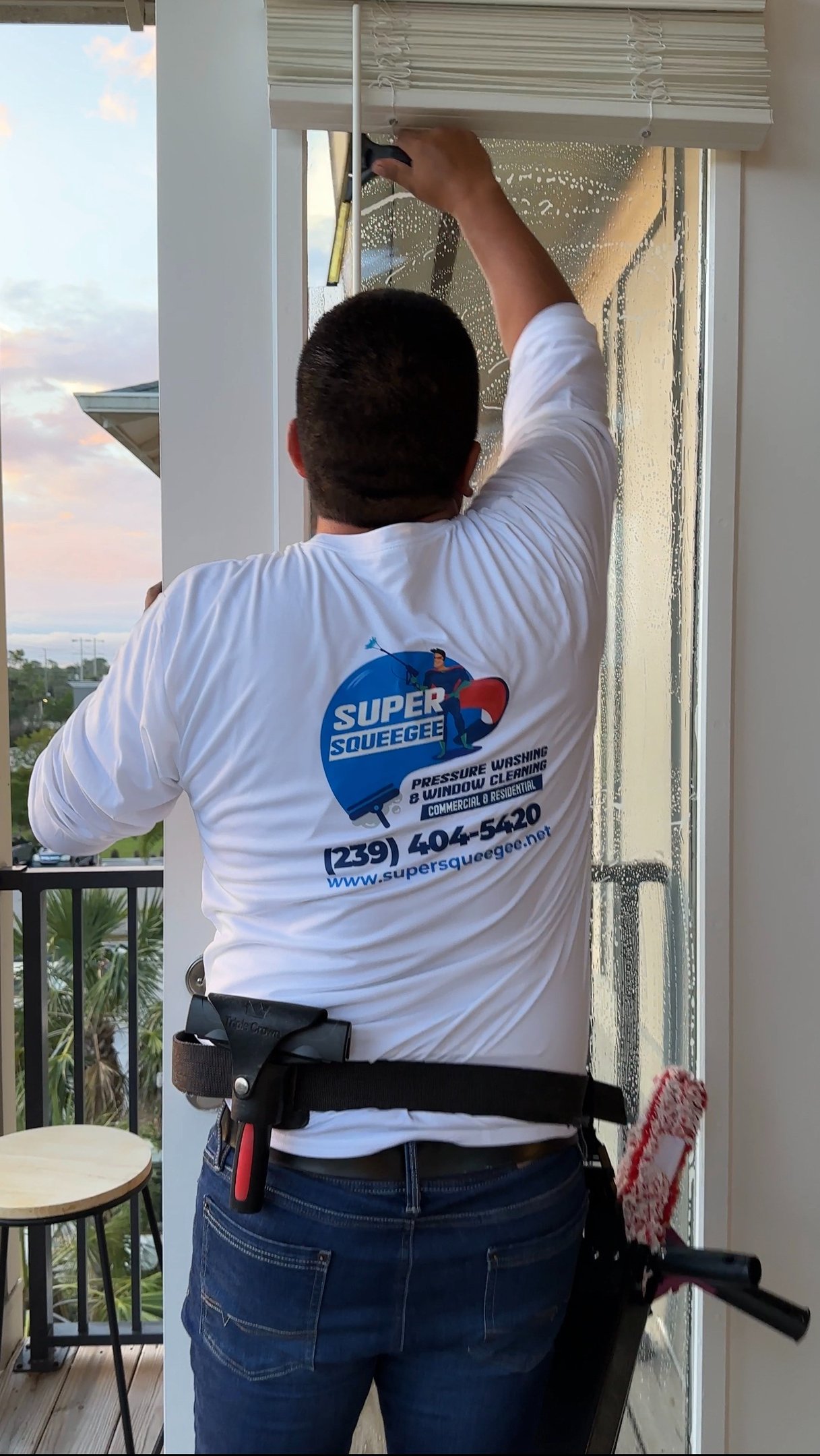 SuperSqueegee technician cleaning residential windows in Naples FL