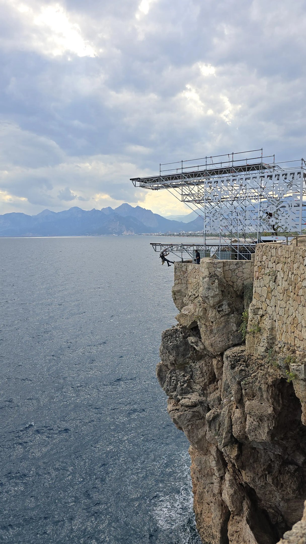 a man standing on a cliff face down into the ocean