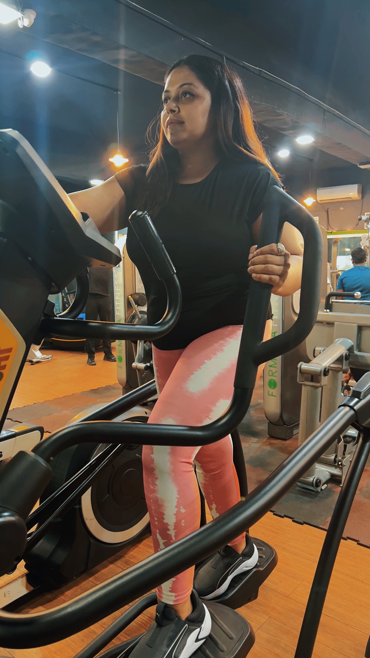 a woman in a black shirt and pink leggings on a stationary bike