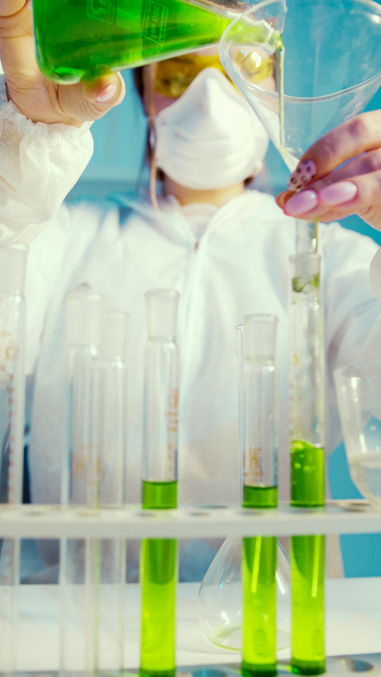 a person in a lab coat is pouring liquid into a beaker