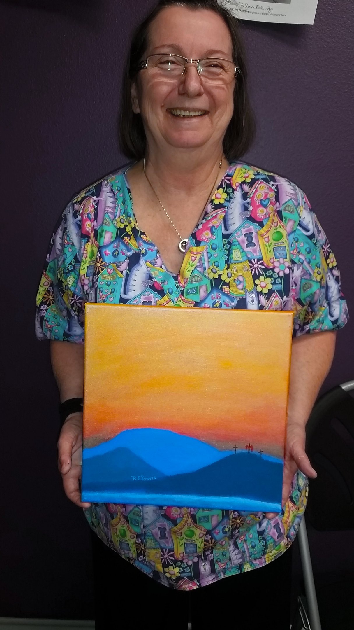 a woman holding a painting of a mountain scene with three crosses