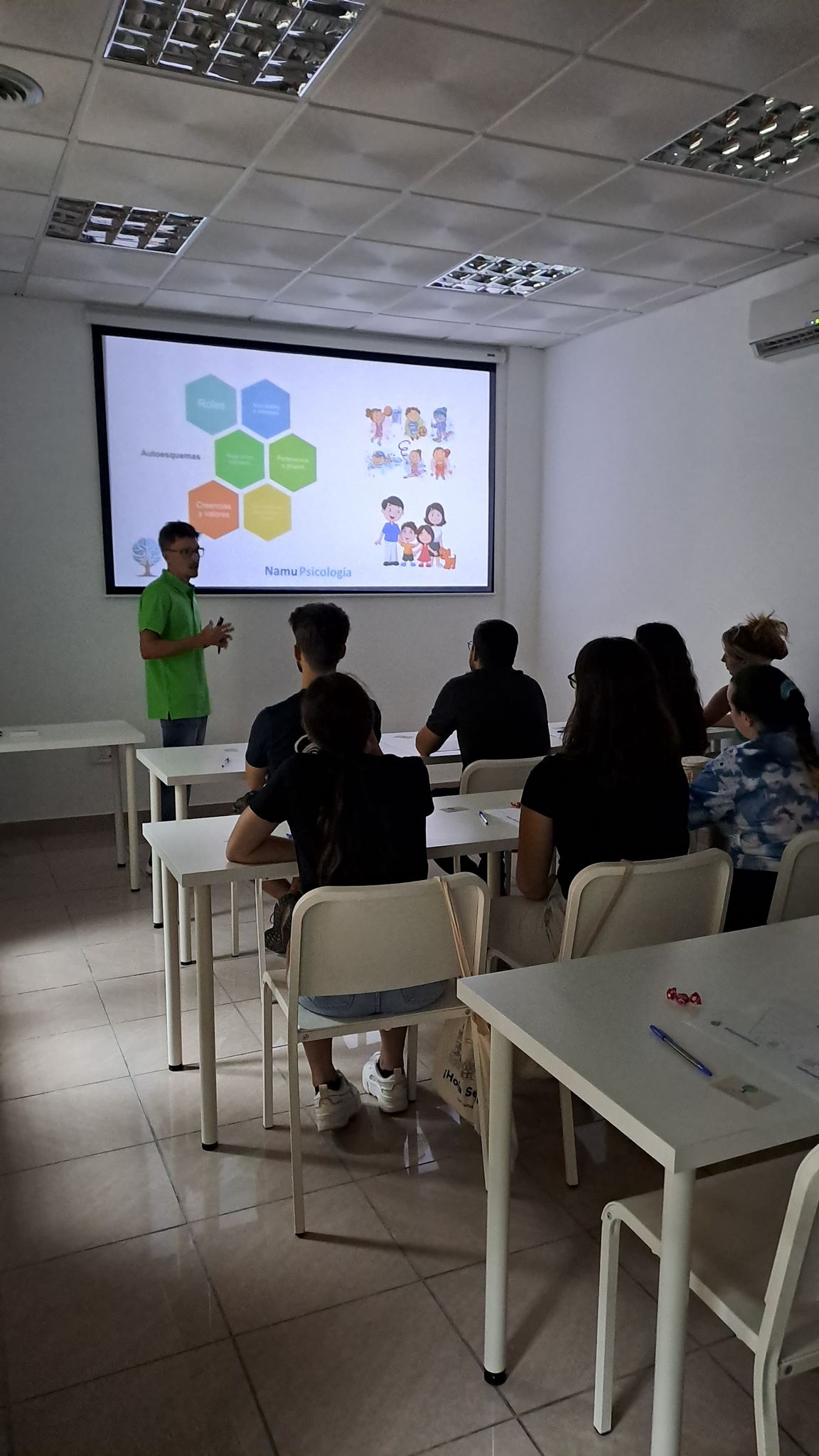 a man standing in front of a classroom with a projector