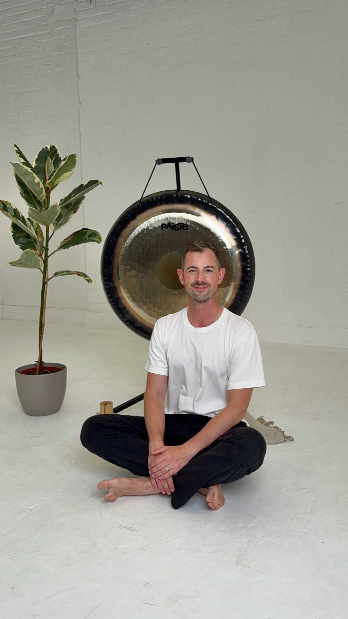 a man sitting in front of a gong in a calming space