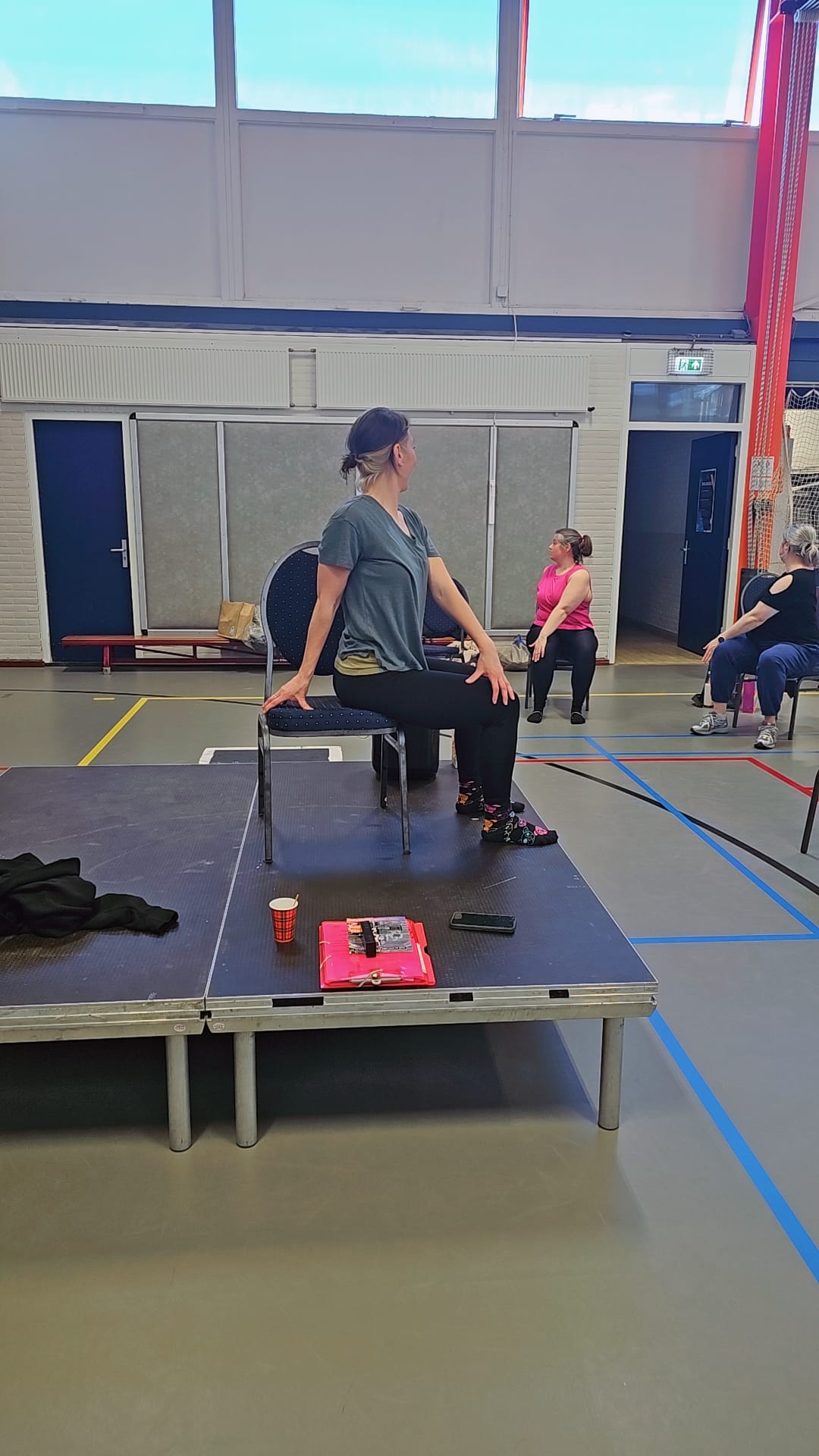 Dames in een zittende twist, op een stoel, in een gymzaal
