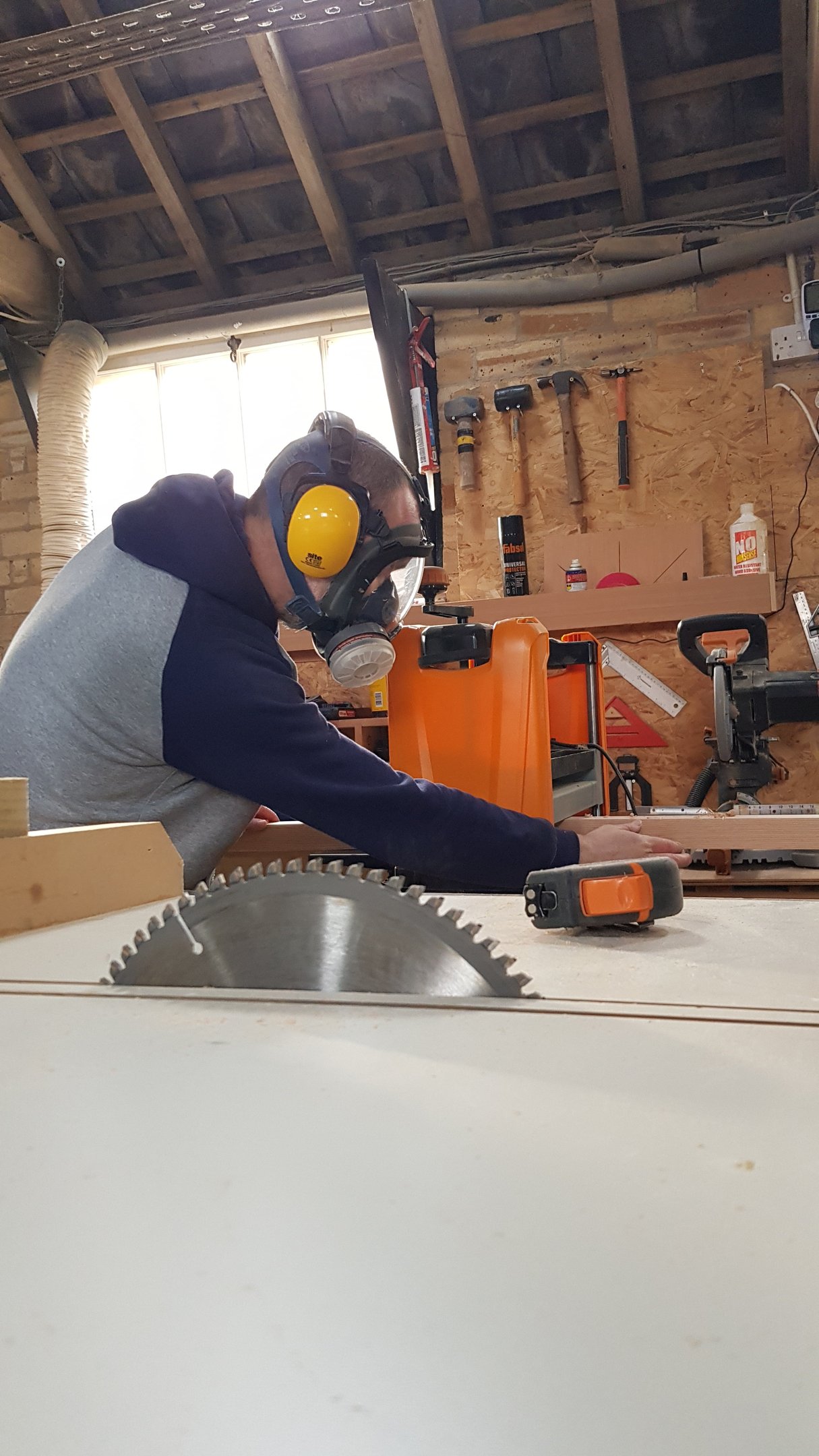 a man in a respirator mask and ear defenders in a workshop