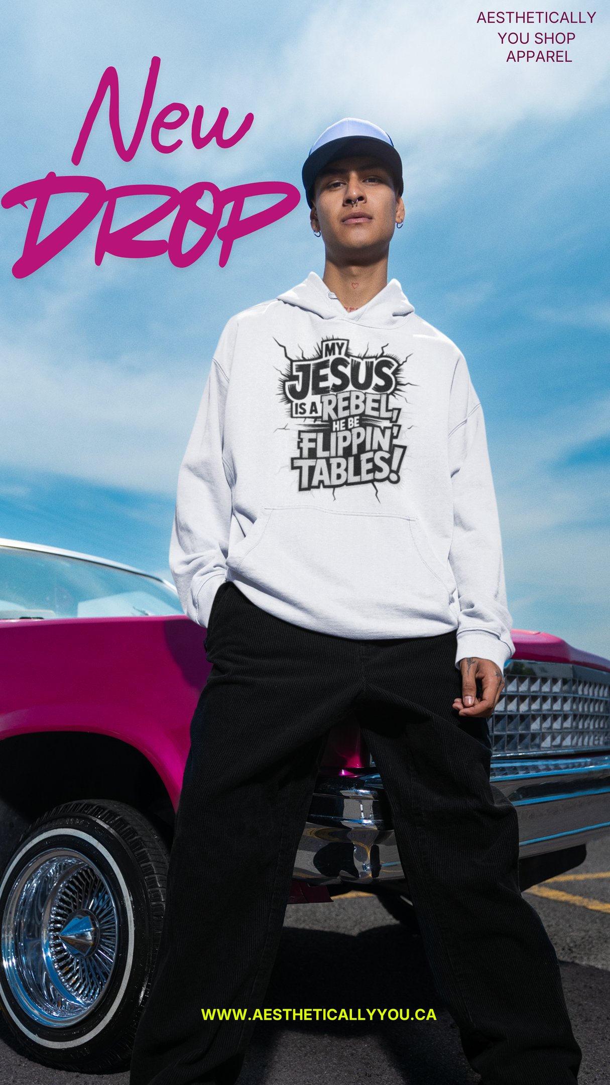 A man wearing a white christian streetwear hoodie with a Jesus is a rebel graphic, standing by a pink car.