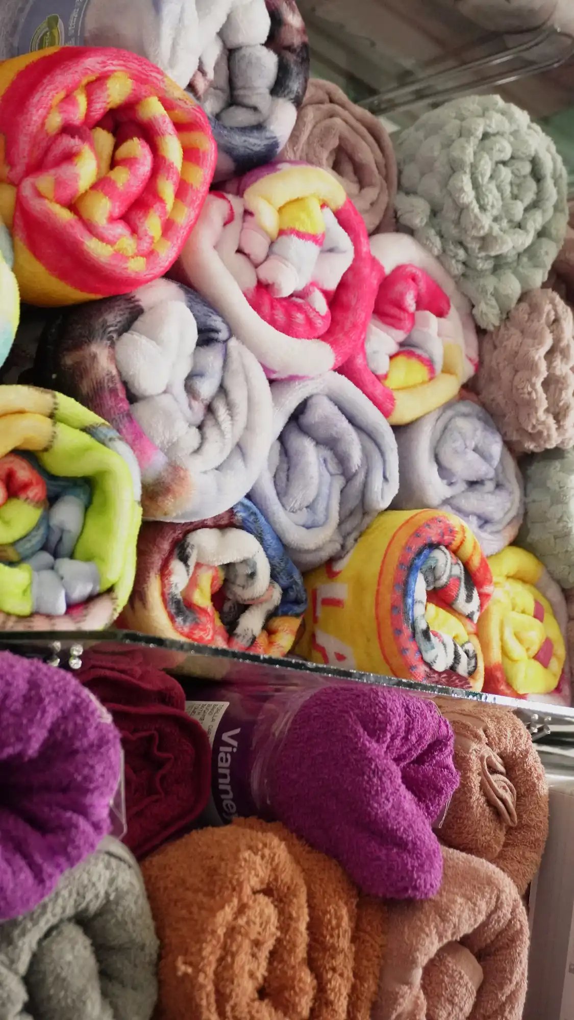 Una fila apilada de diferentes estilos de cobijas en la tienda.