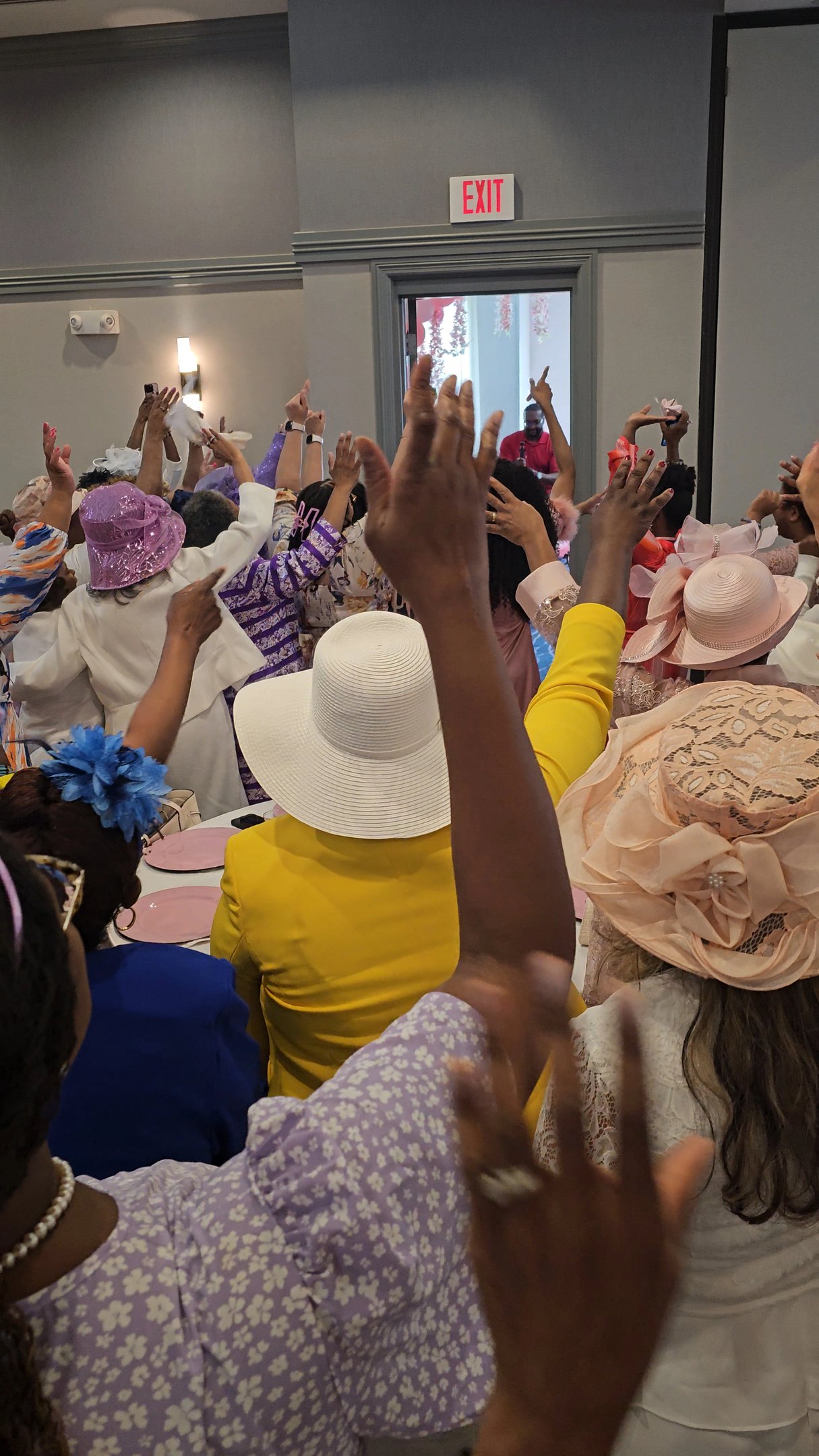 a group of women in hats and hands lifted up