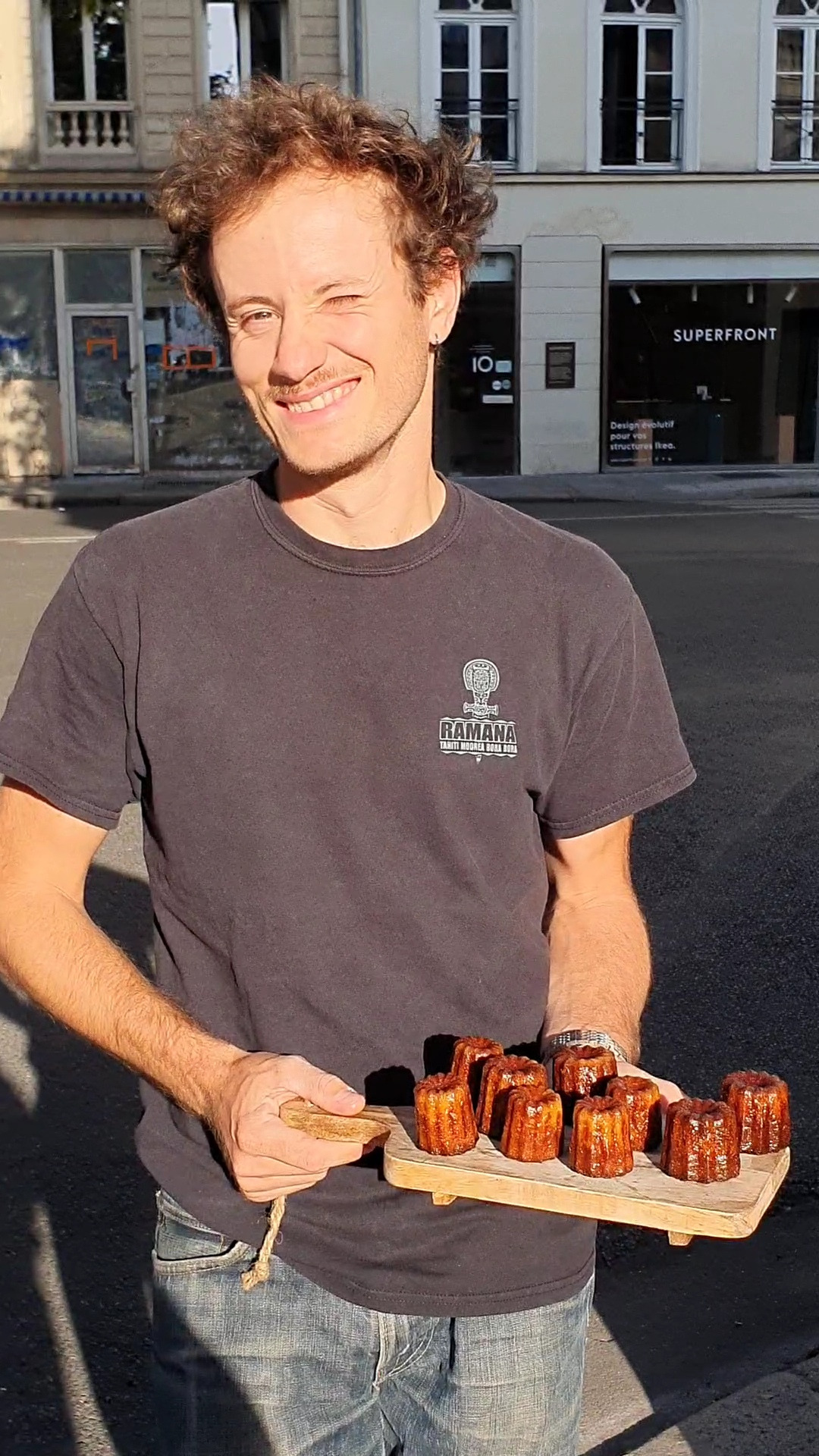 Un homme tient une planche avec des cannelés dessus