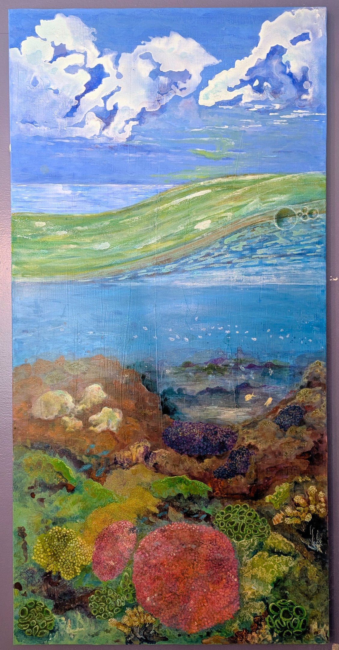 A color rich acrylic painting of coral reef life under a cloudy bright sky and saltwater waves by Kathy LaFollett.